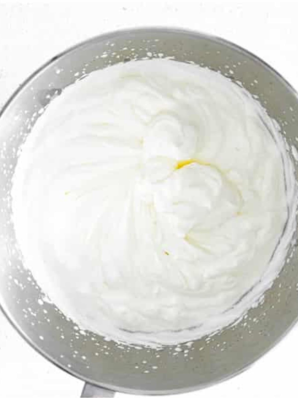 Heavy cream whipped to stiff peaks in a glass bowl.