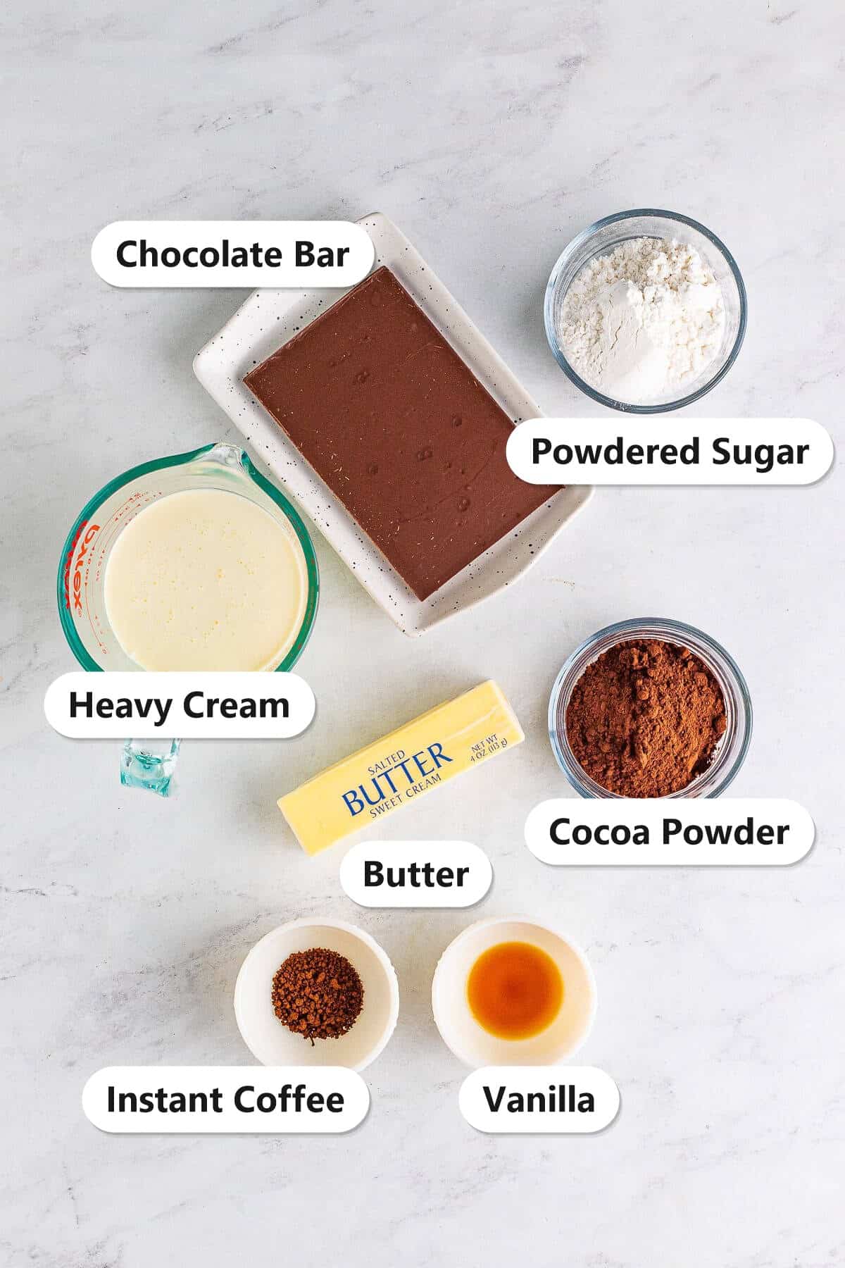 Labeled ingredients for chocolate mousse including a semi-sweet chocolate bar, heavy cream, powdered sugar, cocoa powder, butter, instant coffee, and vanilla.