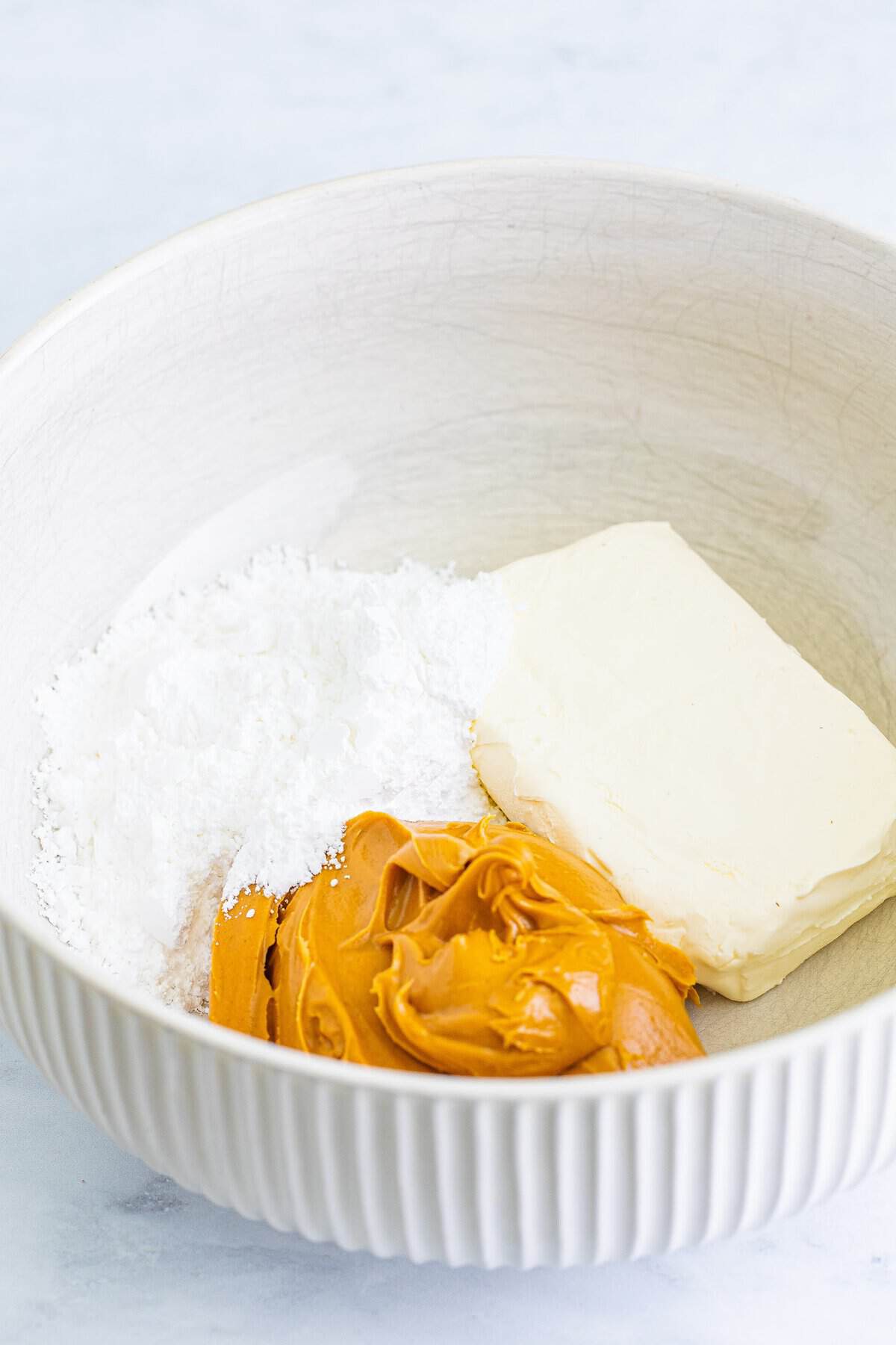 Cream cheese, peanut butter, and powdered sugar in a bowl for chocolate peanut butter pie filling.