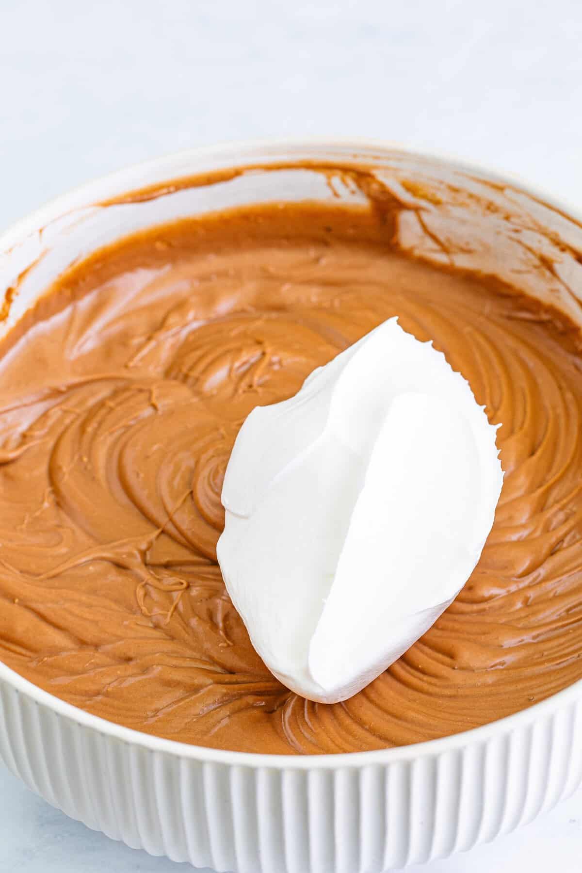 Folding whipped topping into the chocolate peanut butter pie filling.