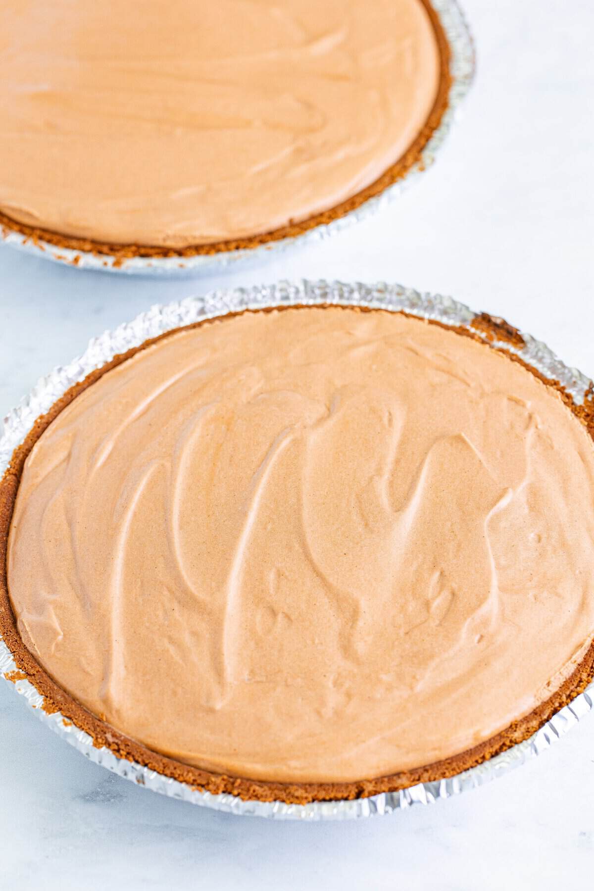Spreading chocolate peanut butter filling into a chocolate cookie pie crust.