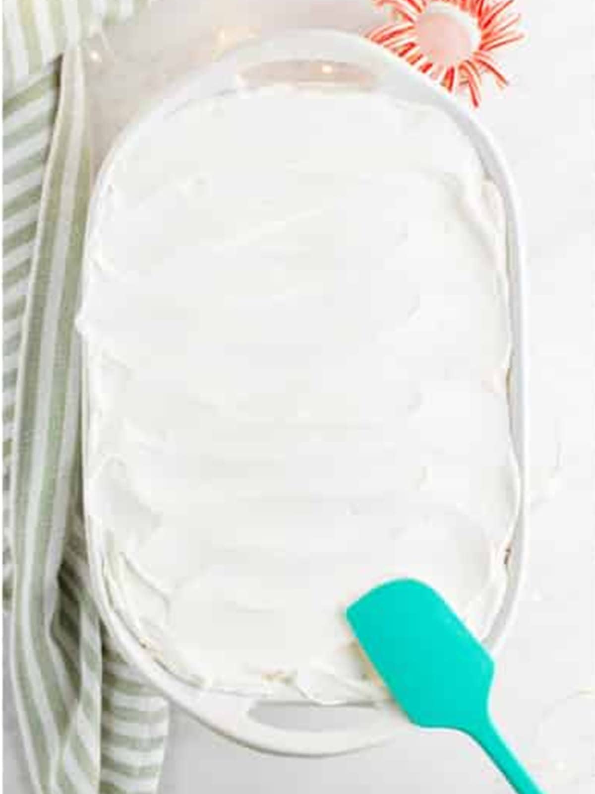 Whipped topping spread over the chilled poke cake.