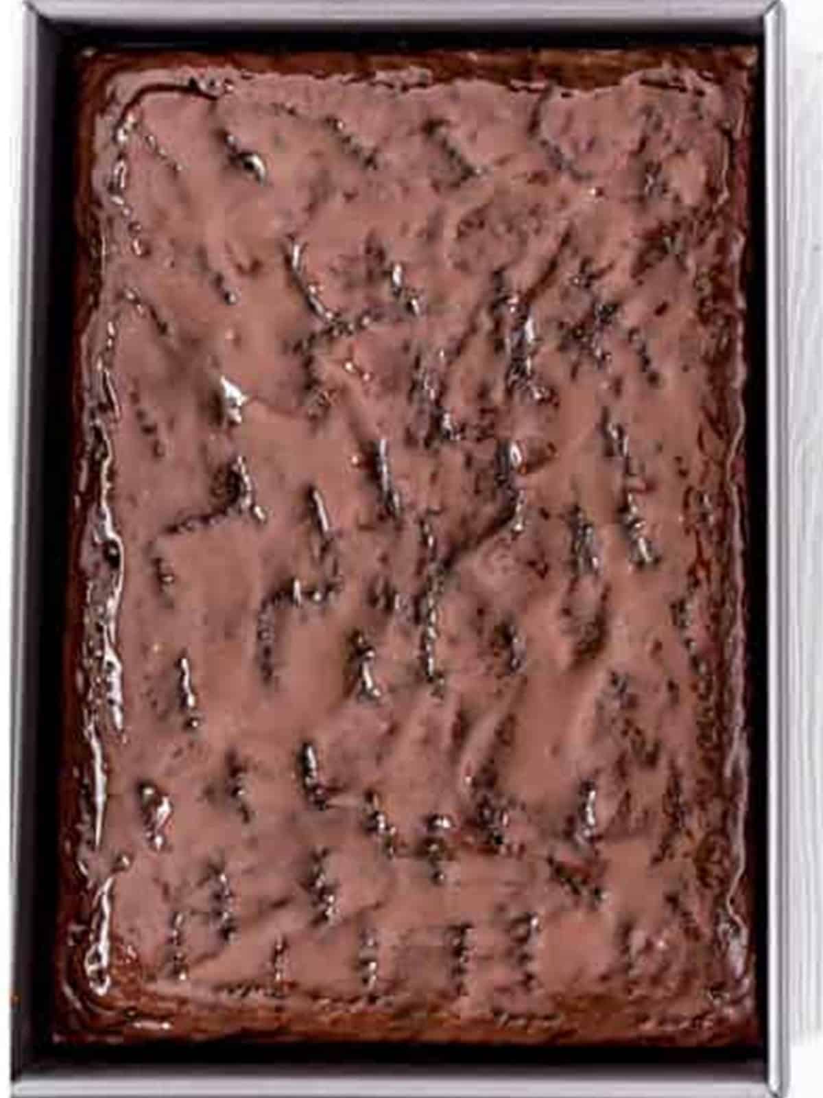 Chocolate cake poked all over with holes ready for filling.
