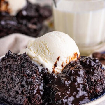 A scoop of warm chocolate pudding cake topped with vanilla ice cream on a plate.