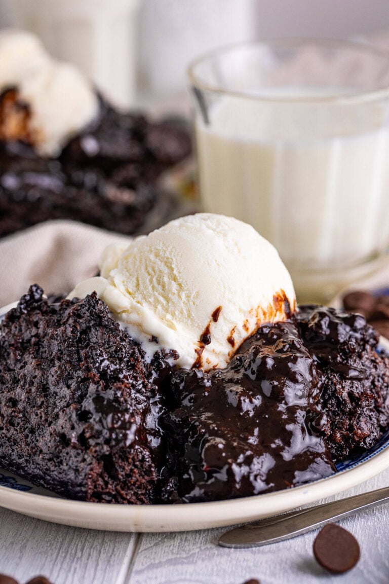A scoop of warm chocolate pudding cake topped with vanilla ice cream on a plate.