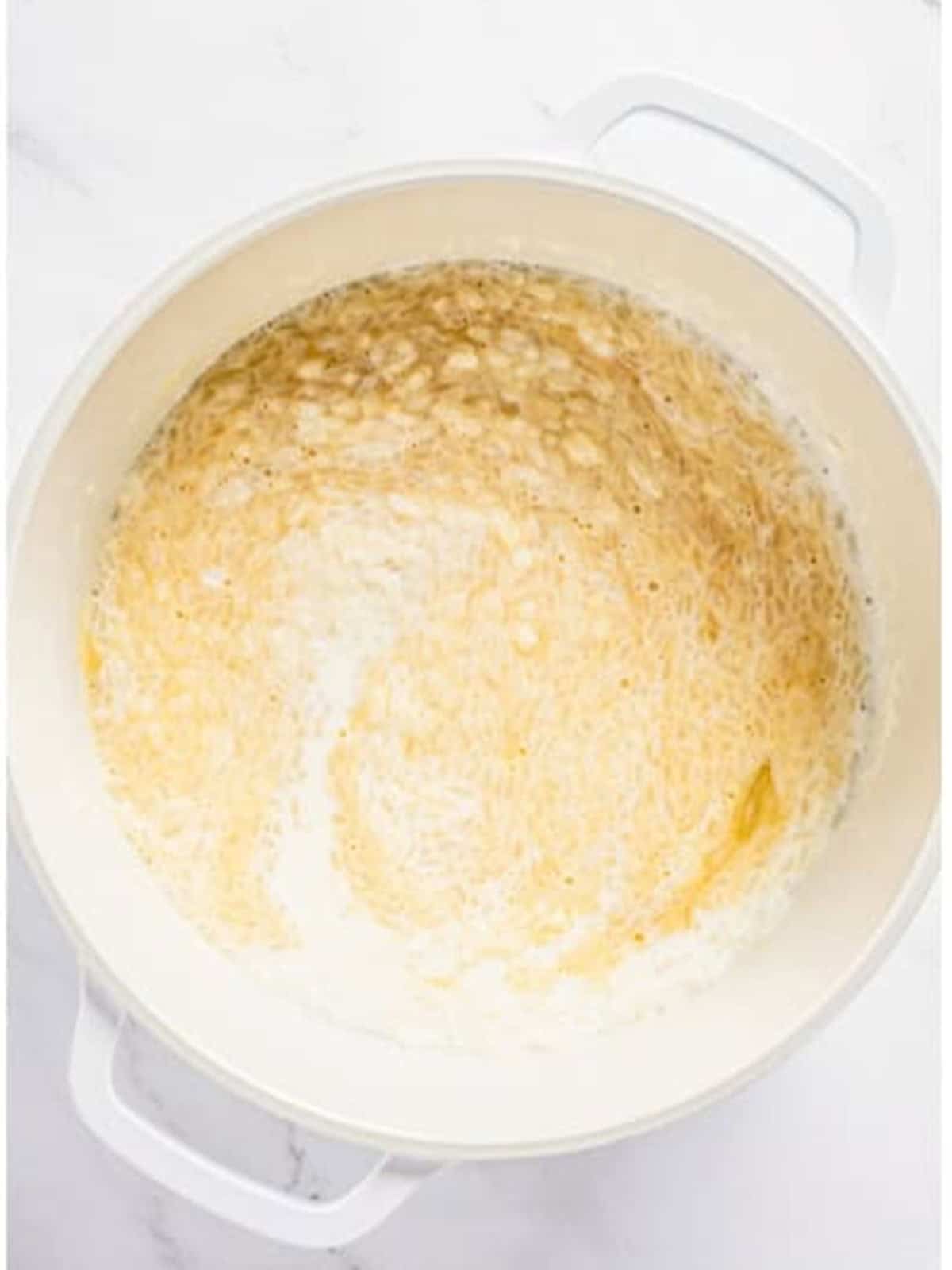 Eggs whisked into the rice and milk in a pot.