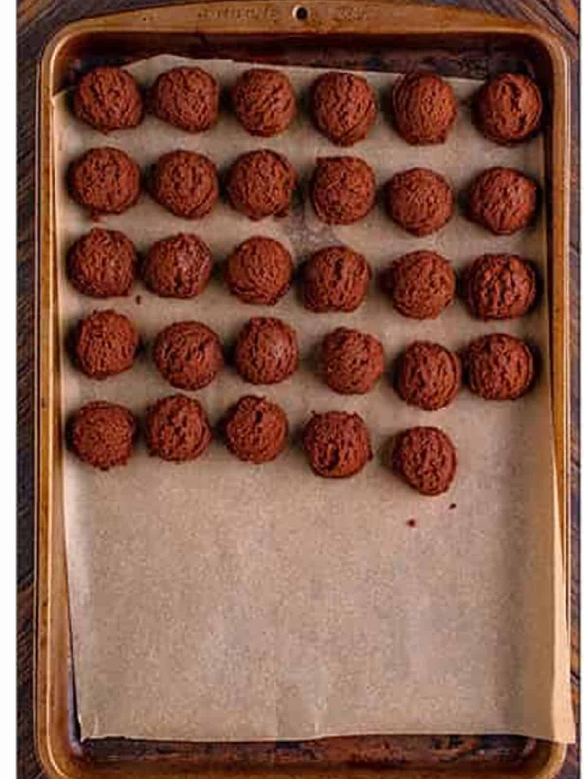 Chocolate sugar cookie dough rolled into balls on a tray.