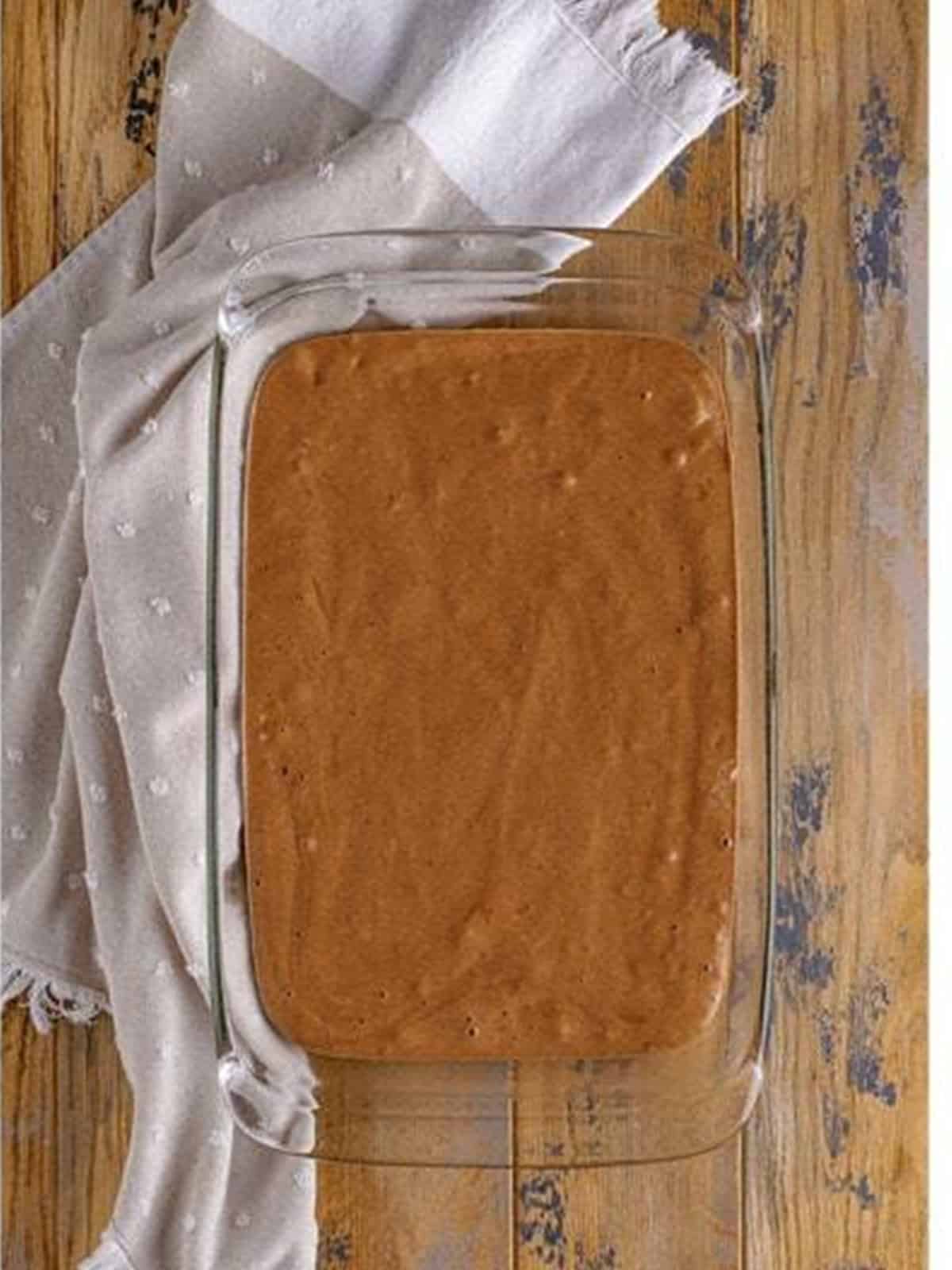 Chocolate cake batter poured into a 9 by 13 baking dish.