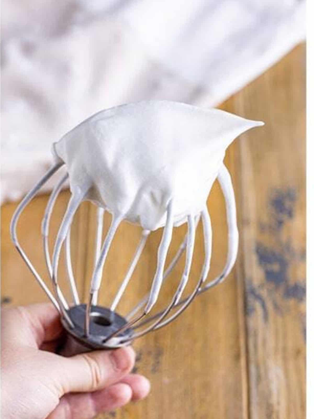 Whipped egg whites at stiff peaks on a whisk attachment.