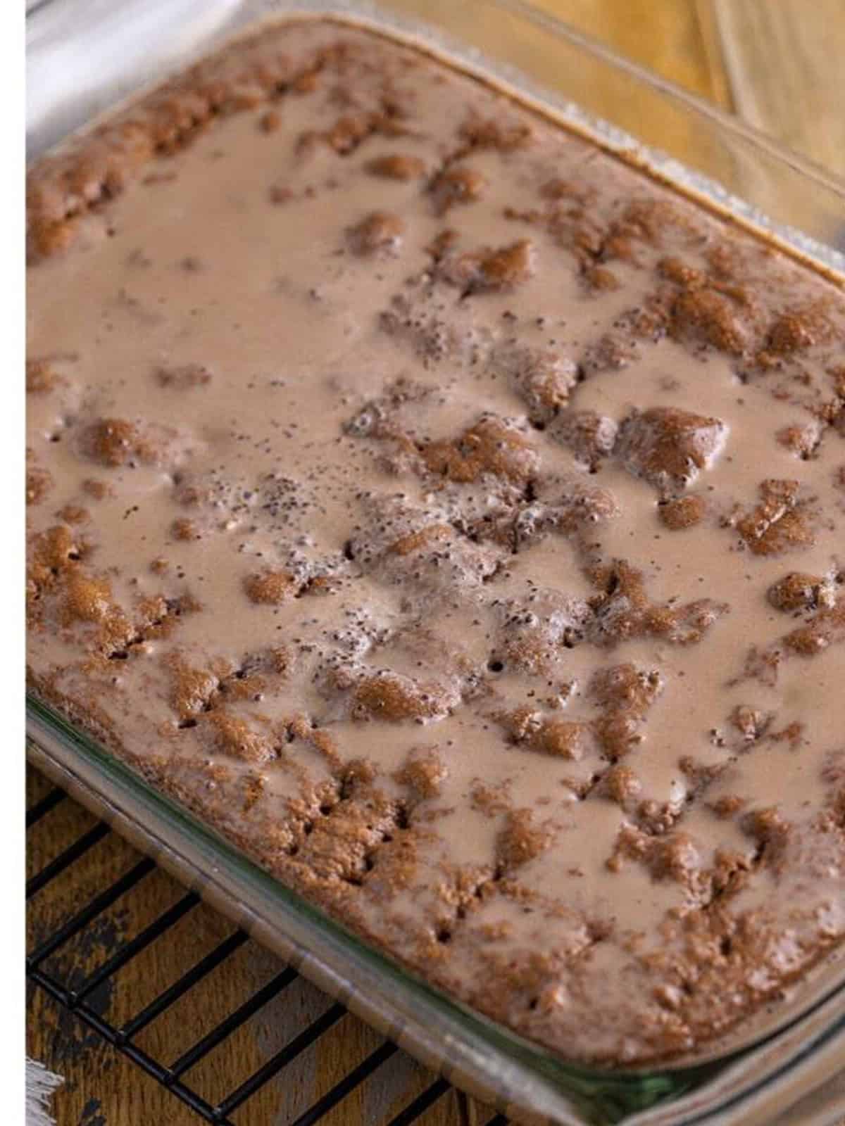 Chocolate milk mixture soaking into a poked chocolate cake.