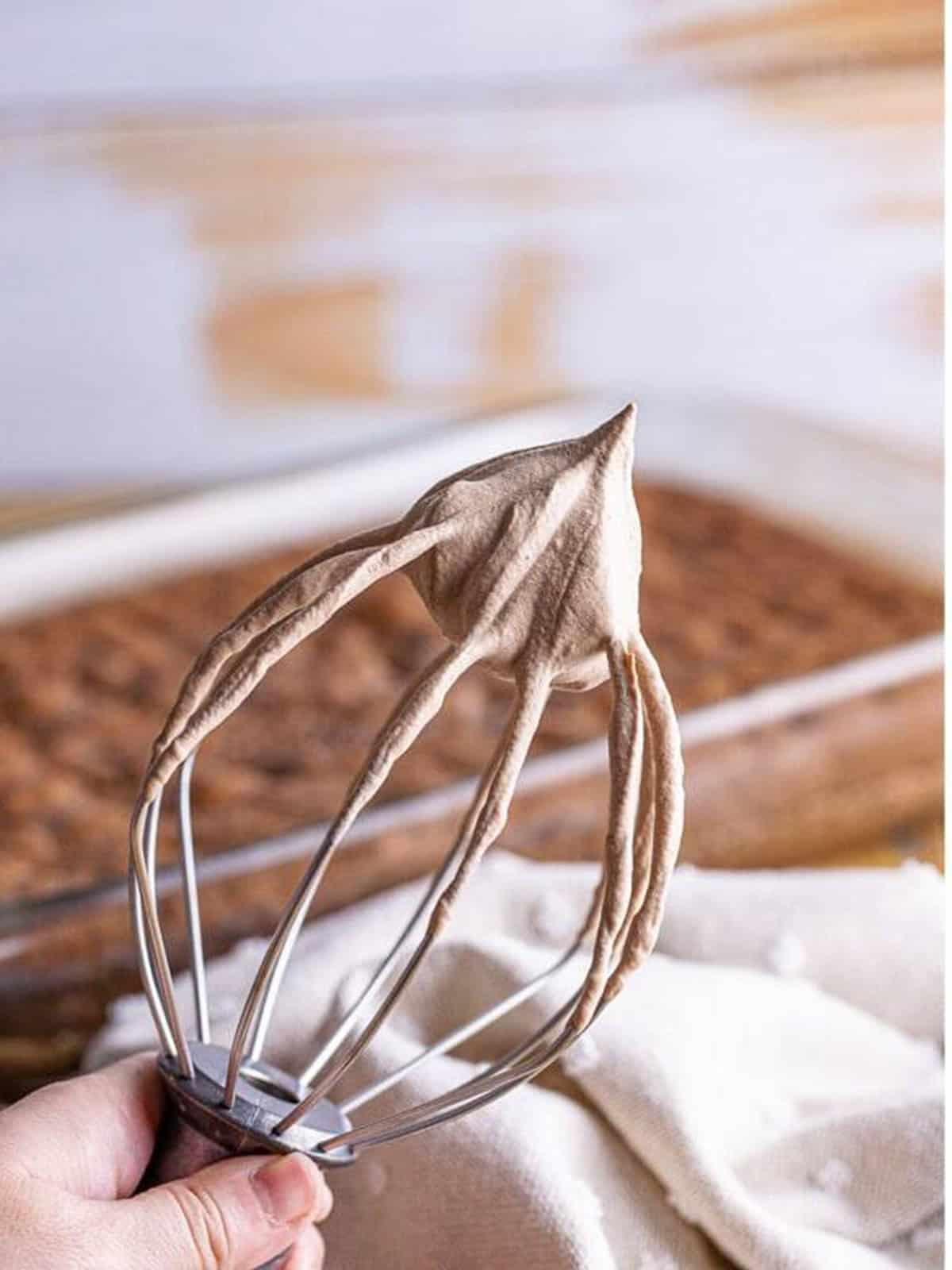 Chocolate whipped cream topping at stiff peaks on a whisk.