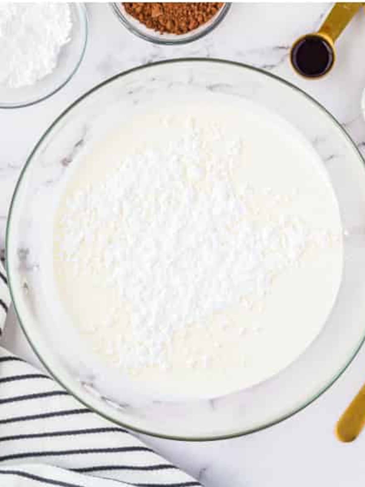 Cold heavy cream and powdered sugar in a mixing bowl for Chocolate Whipped Cream.