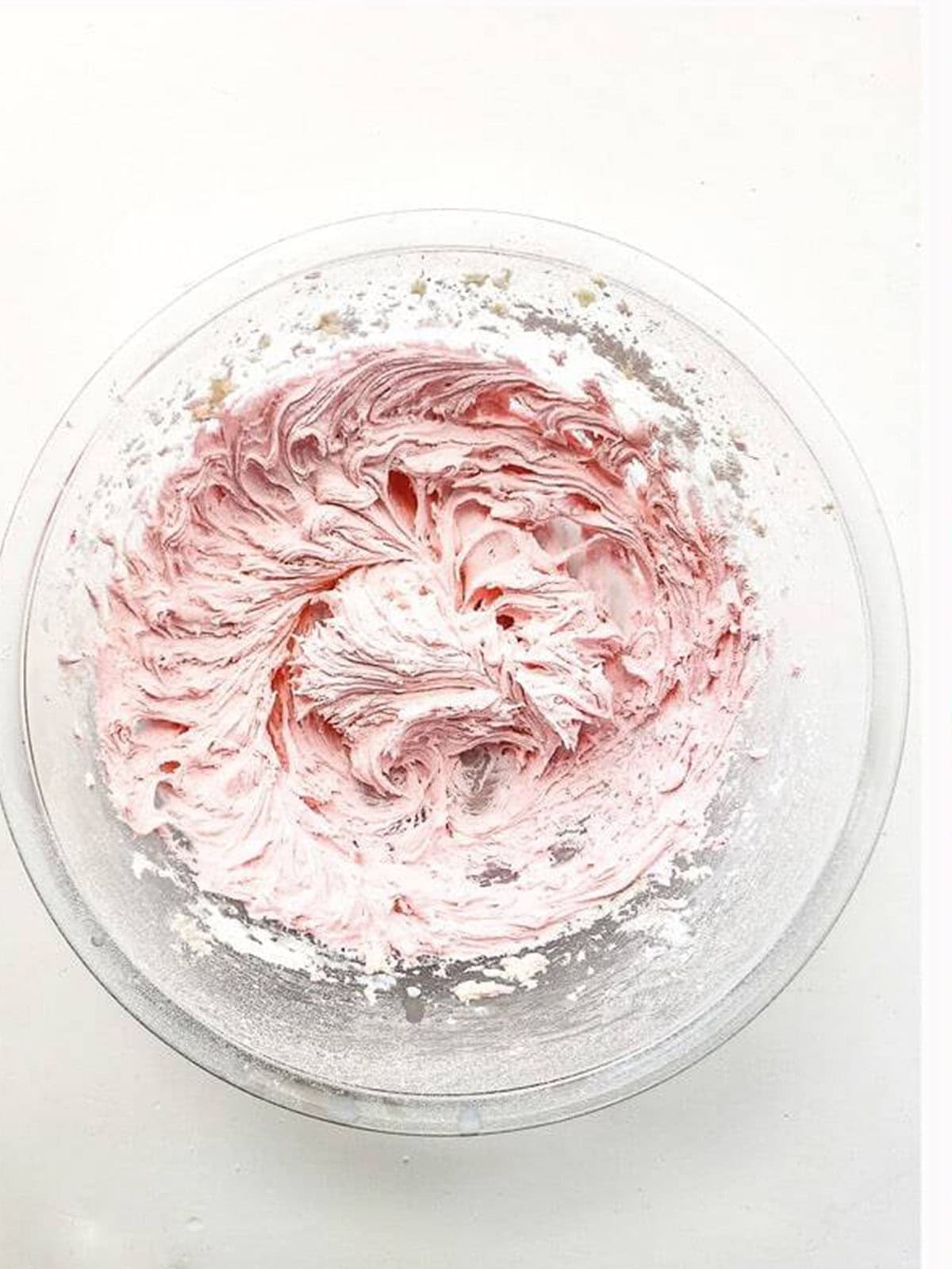 Whipping fluffy pink strawberry frosting in a bowl for whoopie pies.