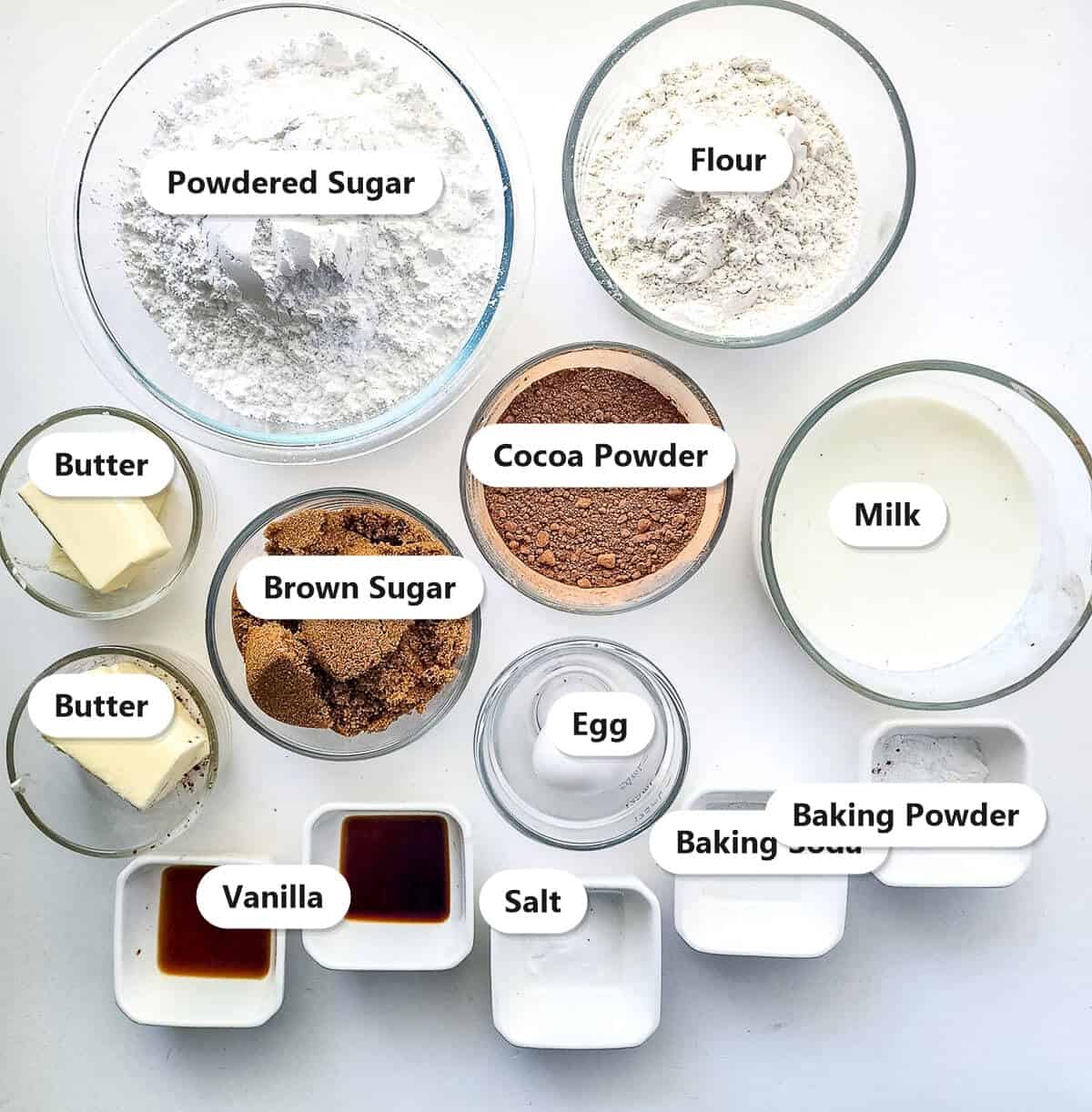 Labeled ingredients for chocolate whoopie pies including flour, cocoa powder, brown sugar, butter, milk, and powdered sugar.
