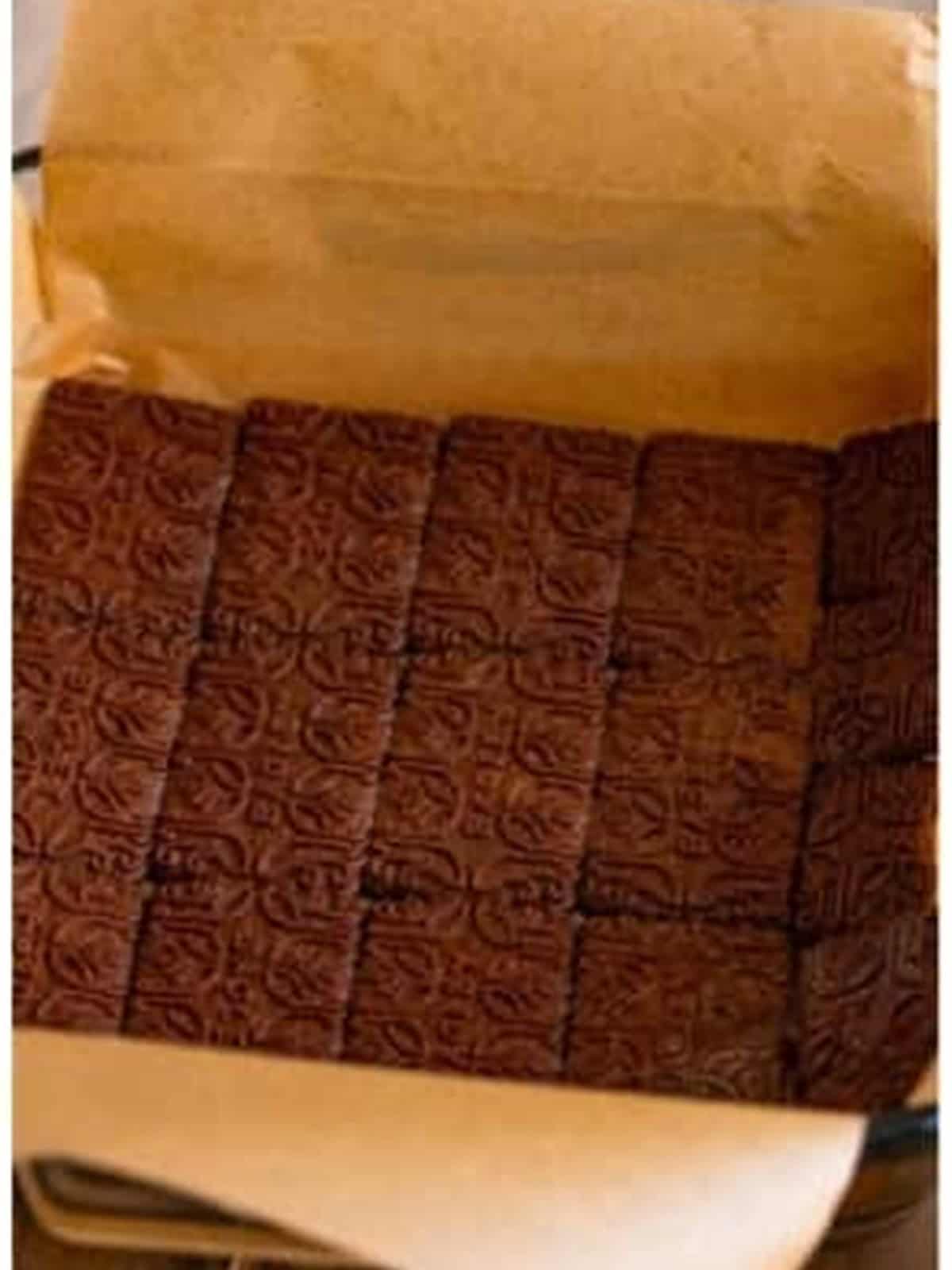 Coffee dipped Chocolinas cookies lining the bottom of a parchment lined baking dish.