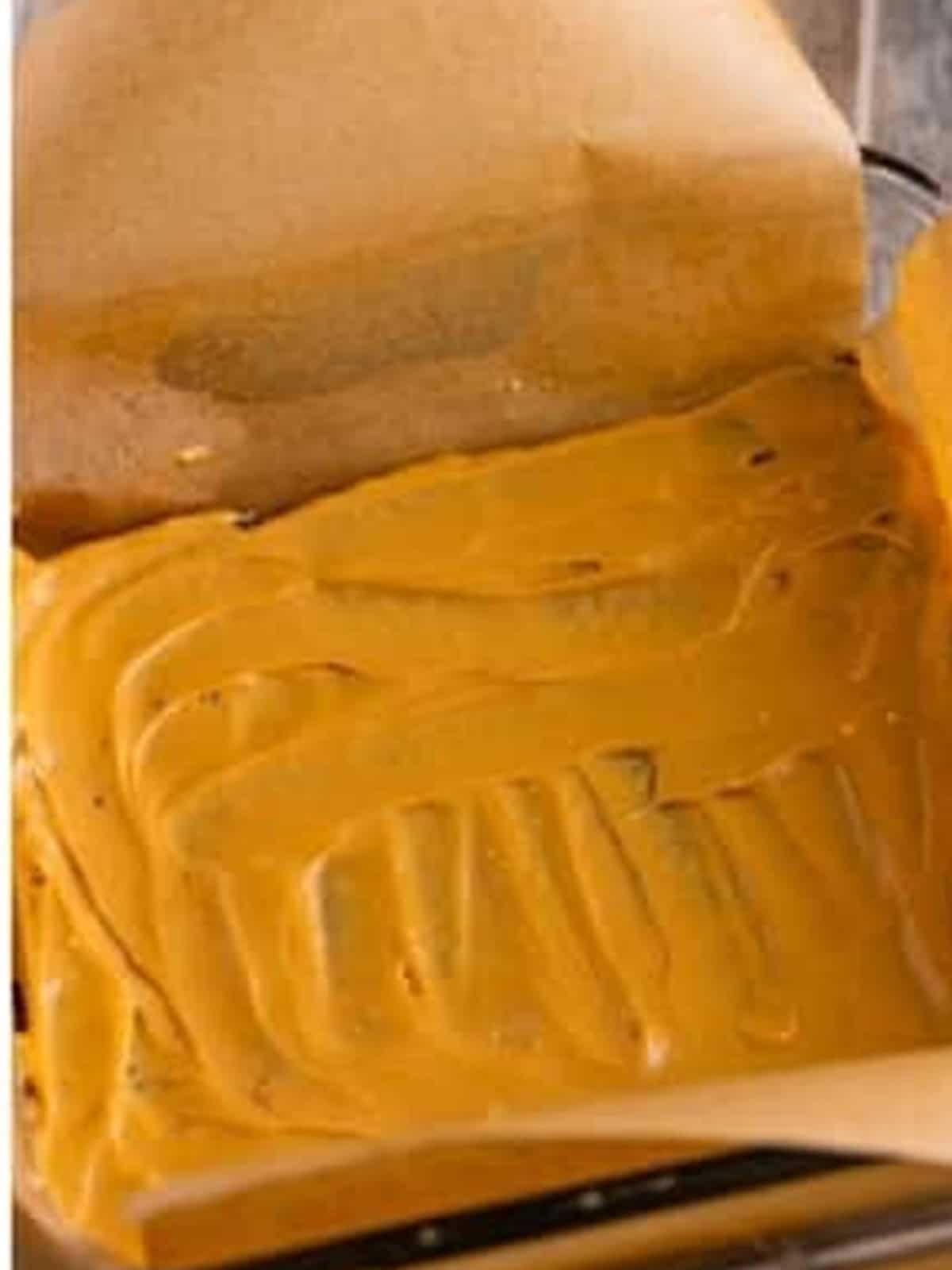 Spreading a layer of dulce de leche cream cheese filling over the cookie layer.