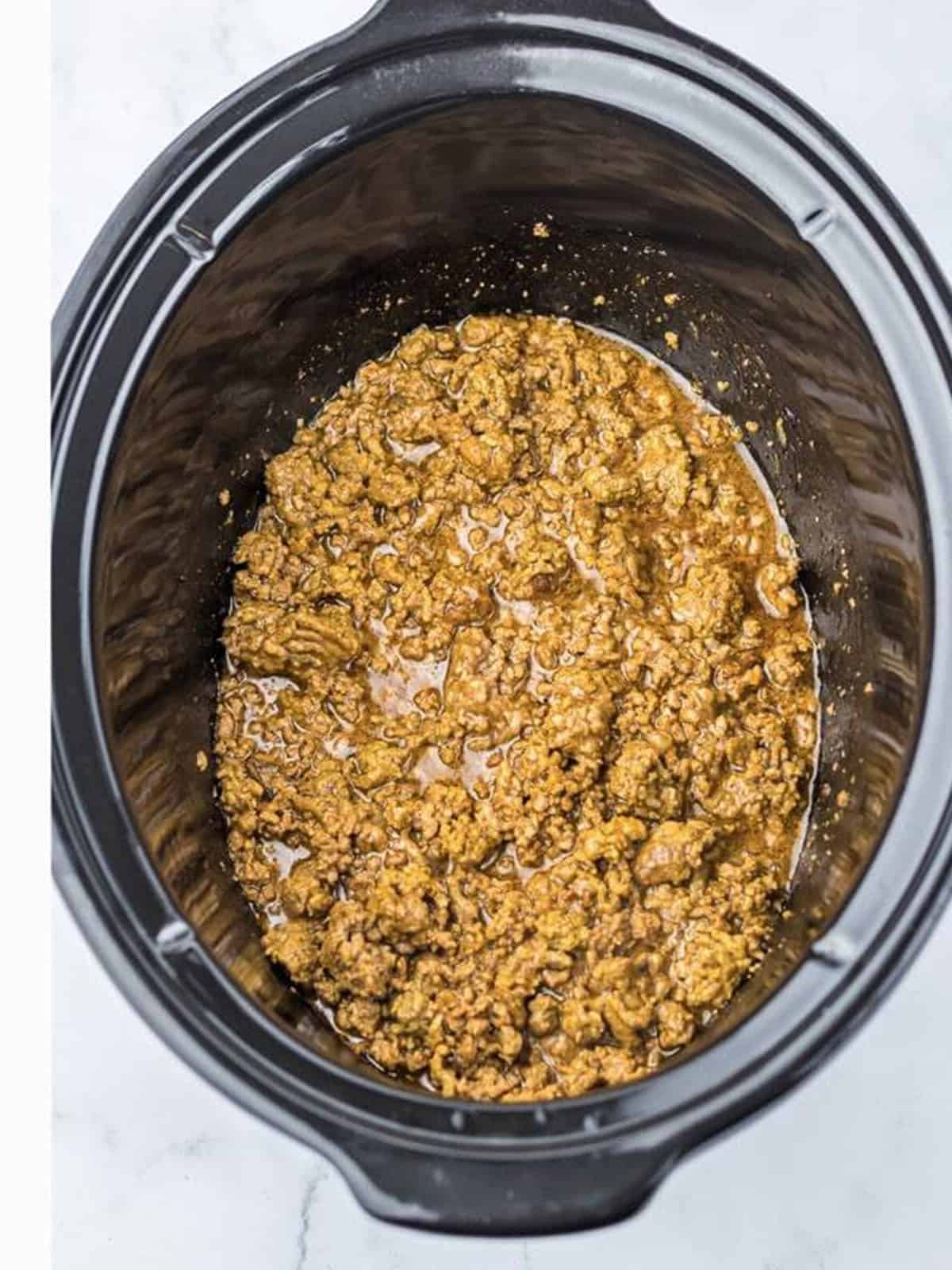 Seasoned beef cooked with beef broth in the slow cooker for chopped cheese.
