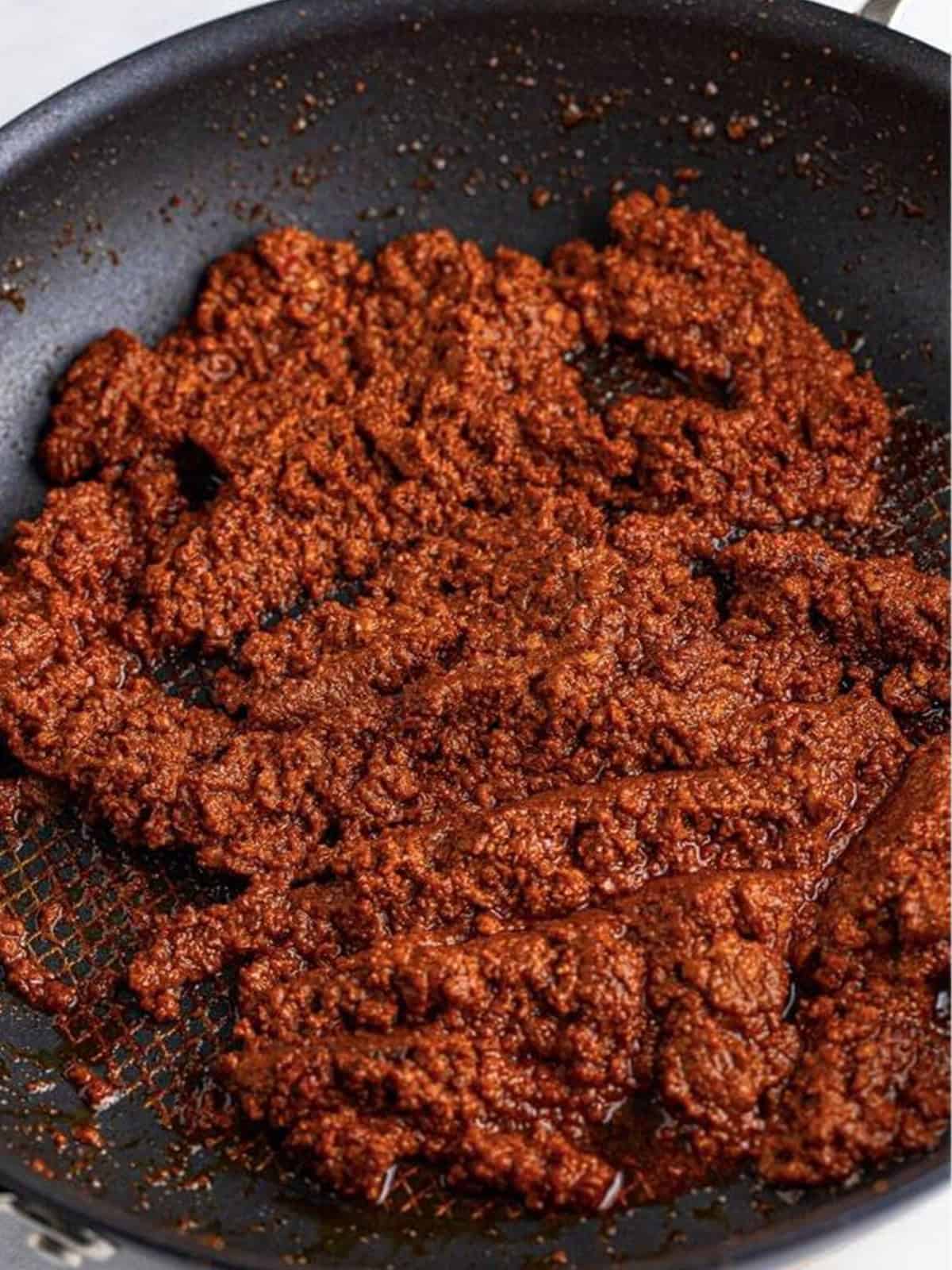 Cooked and crumbled chorizo in a skillet for crock pot queso dip.