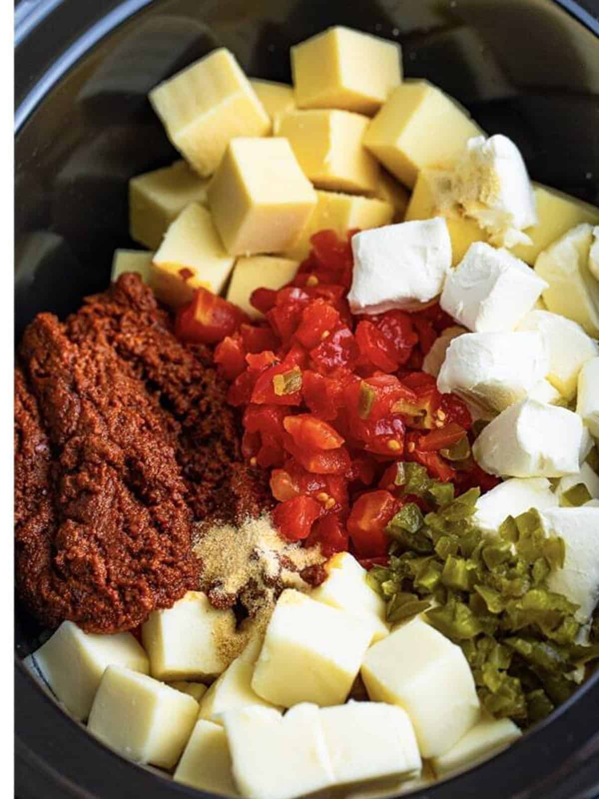 Cheese cubes, tomatoes with green chiles, and jalapenos added to a slow cooker with chorizo.