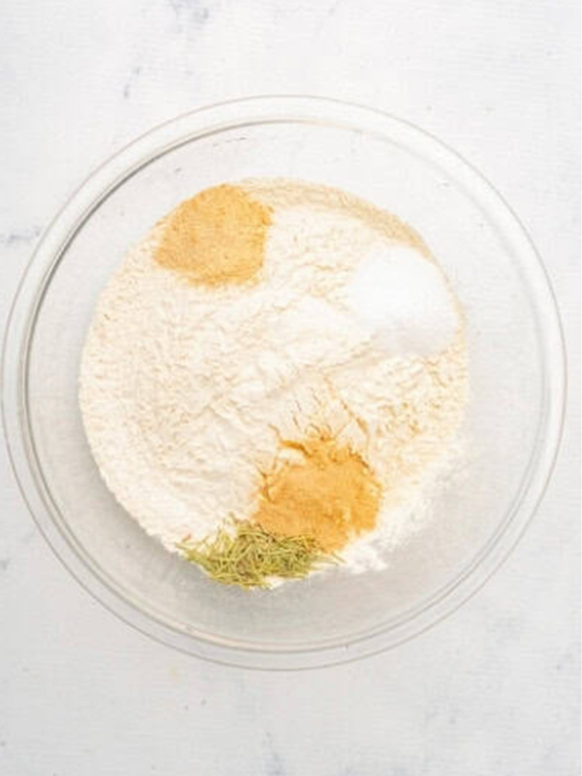 Bread flour, rosemary, and garlic powder mixed in a bowl