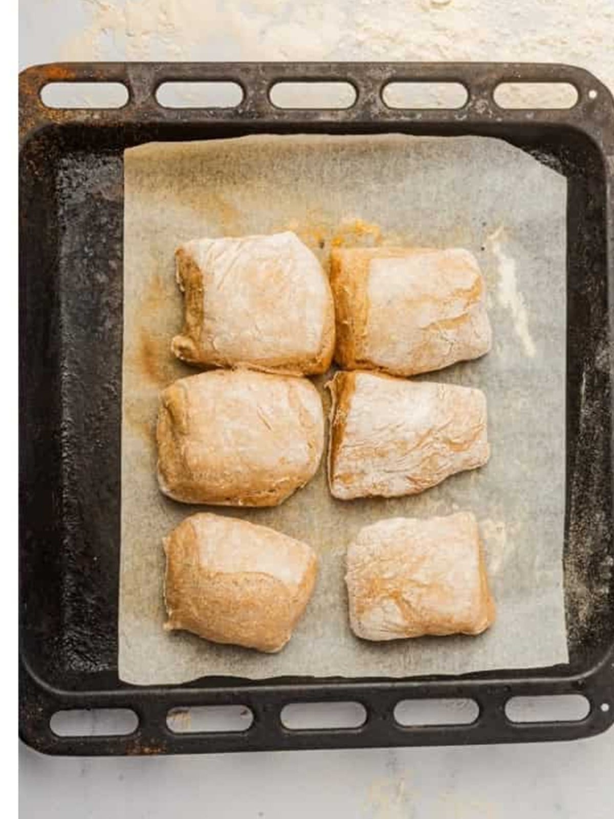 Proofed ciabatta rolls on a parchment-lined tray
