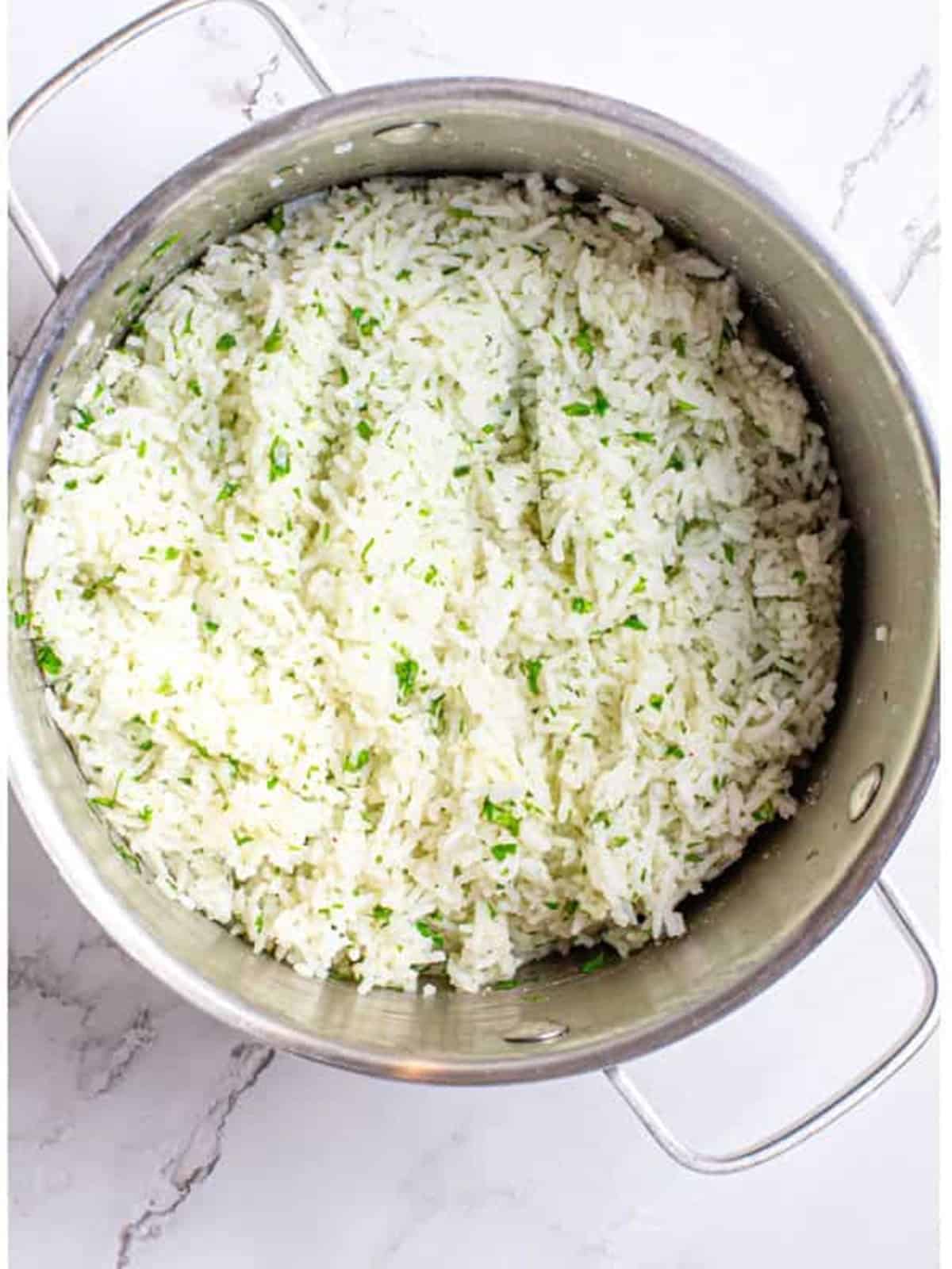 Cilantro lime rice tossed with butter, fresh lime, and chopped cilantro in a pot.