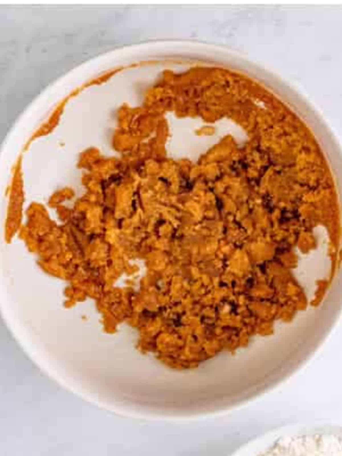 Brown sugar and melted butter stirred together in a white bowl.