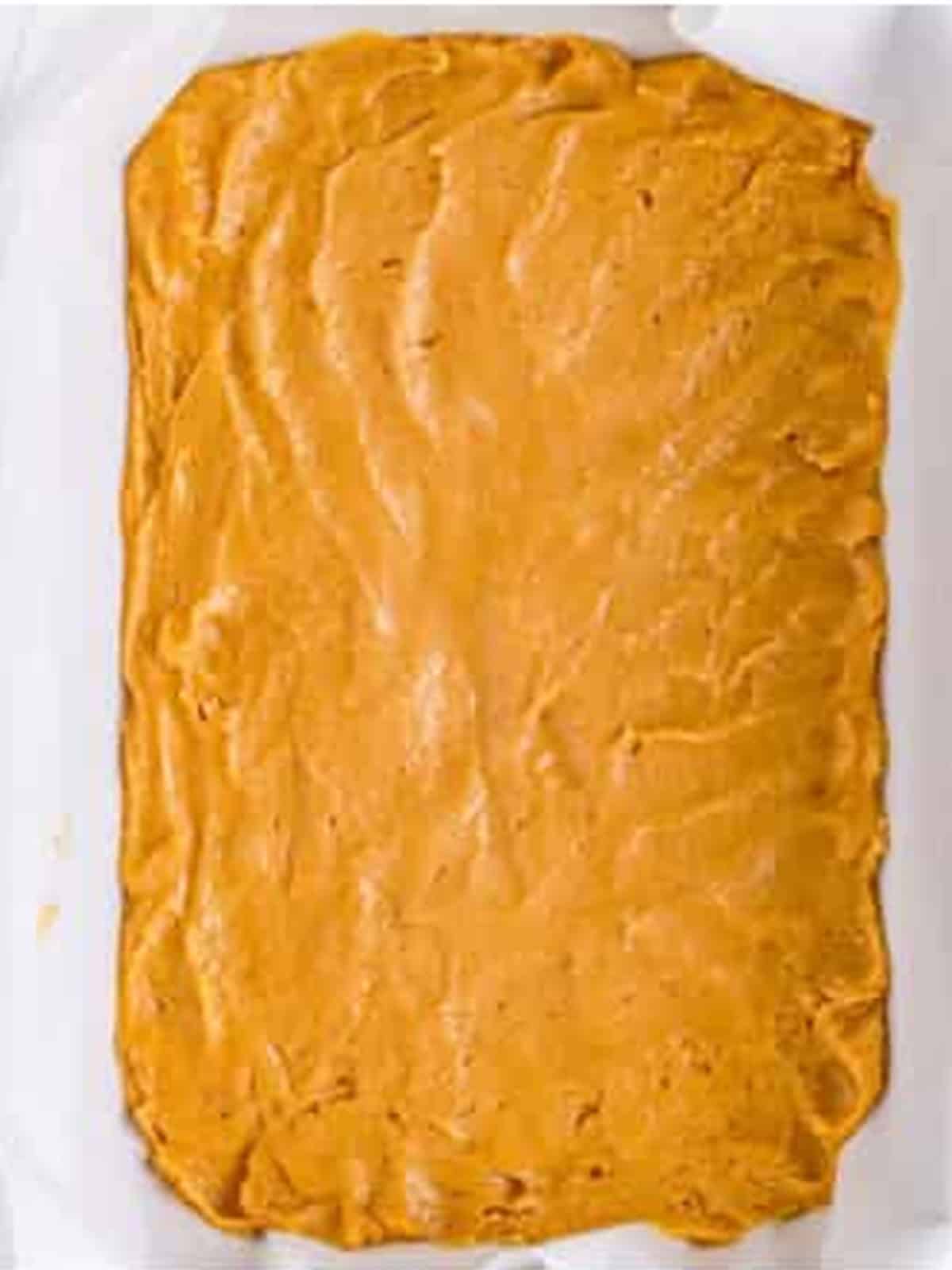 Blondie batter pressed into a parchment lined baking dish.