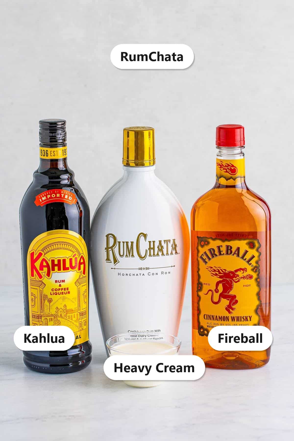 Labeled ingredients for cinnamon roll cocktail including RumChata, Fireball, Kahlua, and heavy cream.