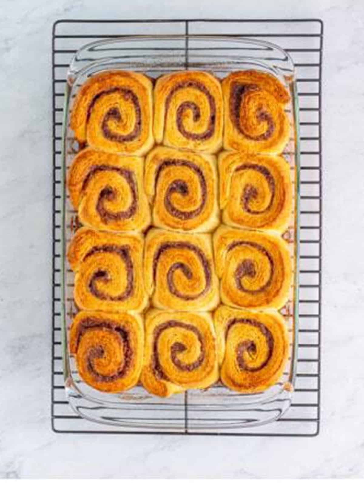 Golden baked cinnamon rolls cooling on a wire rack.