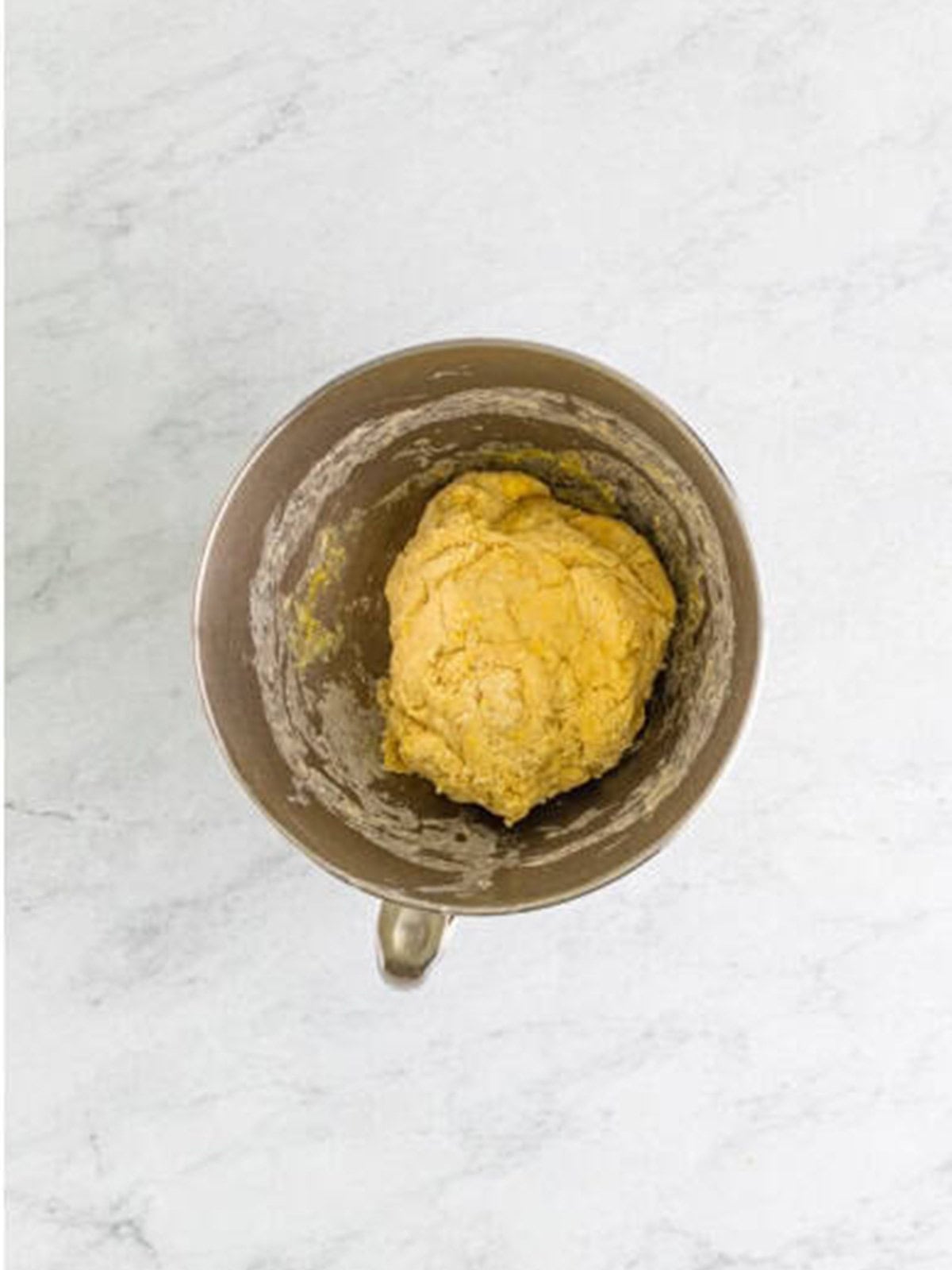 Smooth cinnamon roll dough kneaded in a stand mixer bowl.