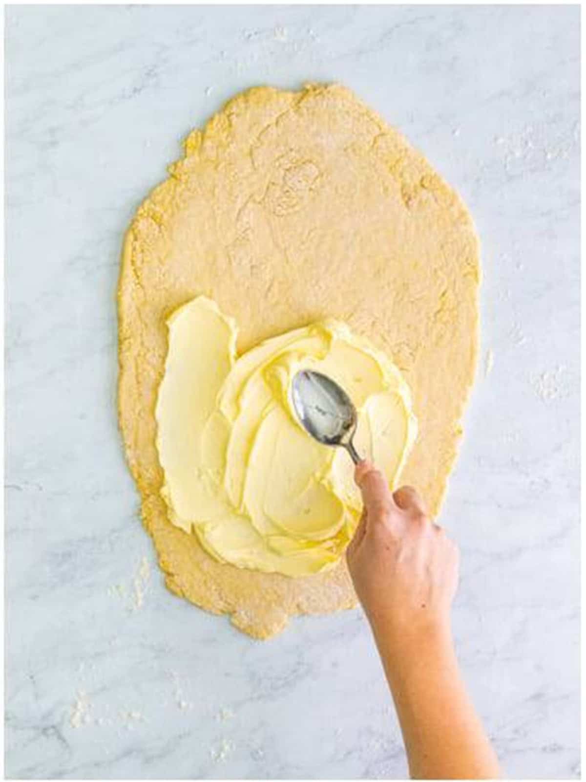 Softened butter spread over the rolled out dough to laminate the cinnamon roll dough.