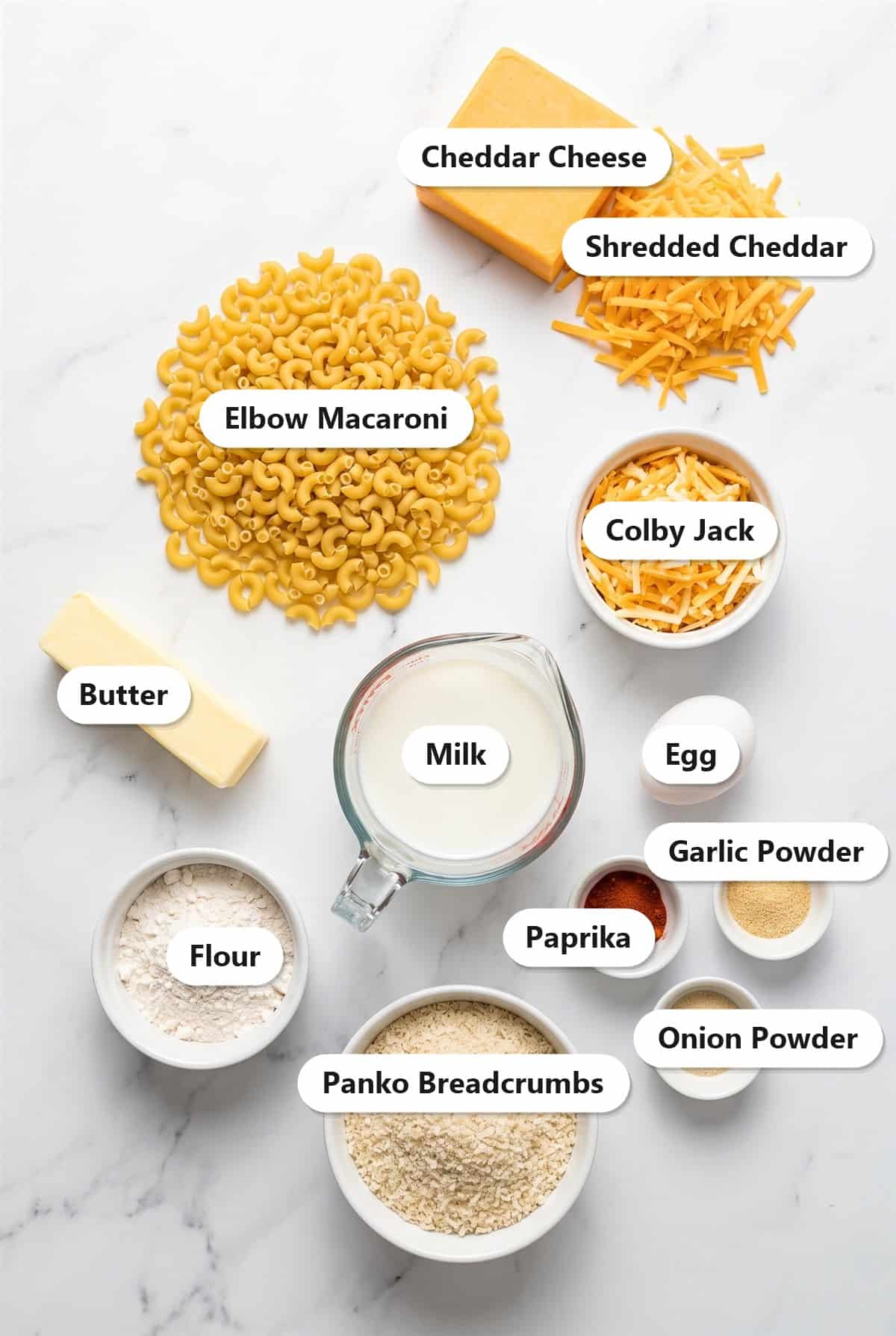 Labeled ingredients for classic baked mac and cheese including elbow macaroni, cheddar cheese, colby jack, butter, milk, egg, flour, panko breadcrumbs, and seasonings.