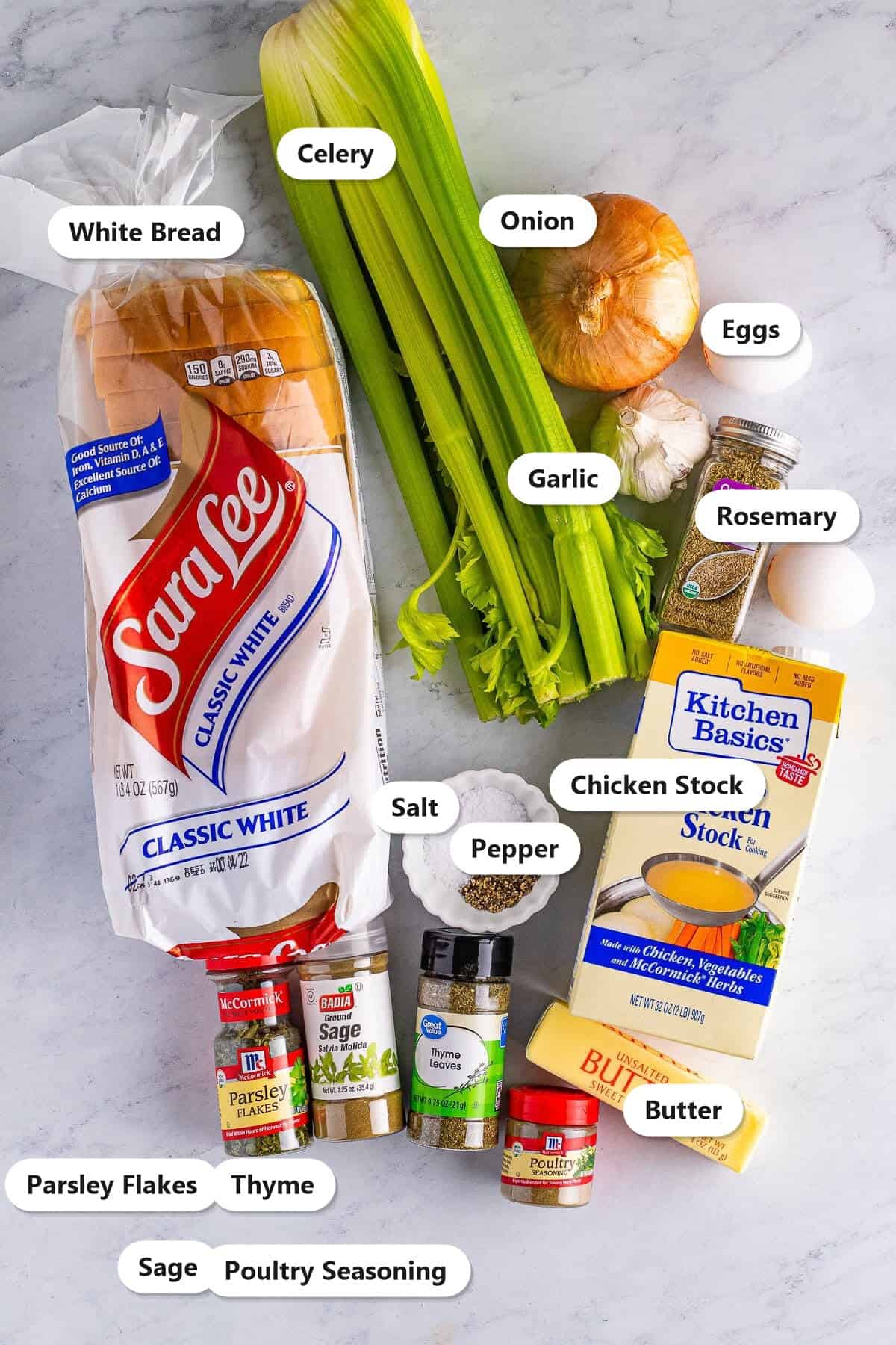 Labeled ingredients to make classic stuffing including white bread, celery, onion, garlic, eggs, chicken stock, butter, salt, pepper, sage, thyme, parsley, rosemary, and poultry seasoning.