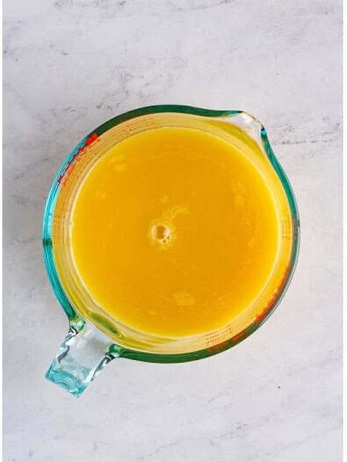 Beaten eggs and chicken stock whisked together in a glass measuring cup.