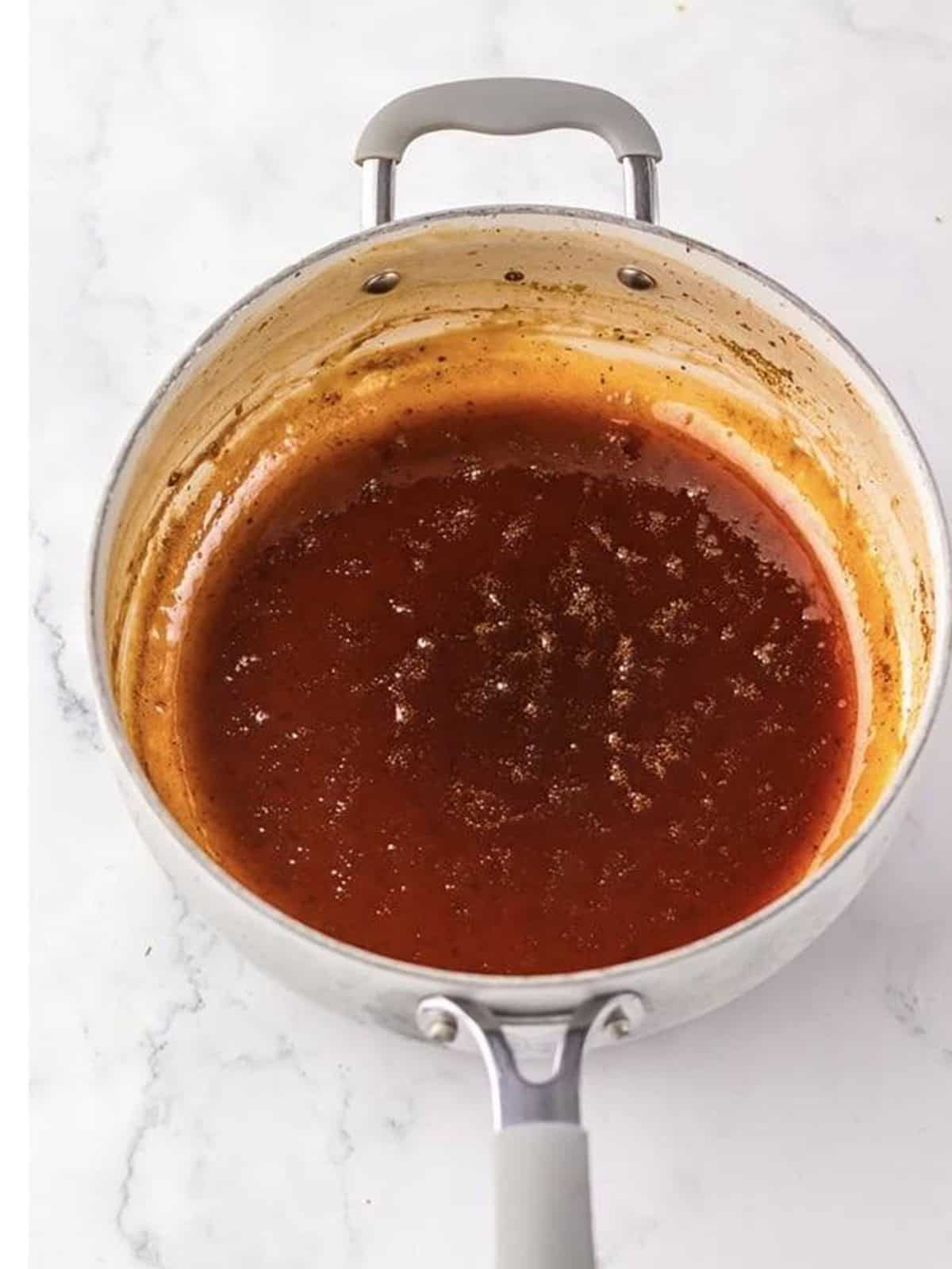 Cherry cola bbq sauce reduced into a glossy glaze in a saucepan.