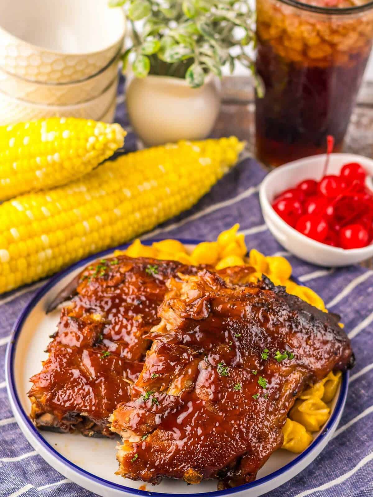 Glazed and broiled Coca-Cola ribs on a plate with corn and mac and cheese.