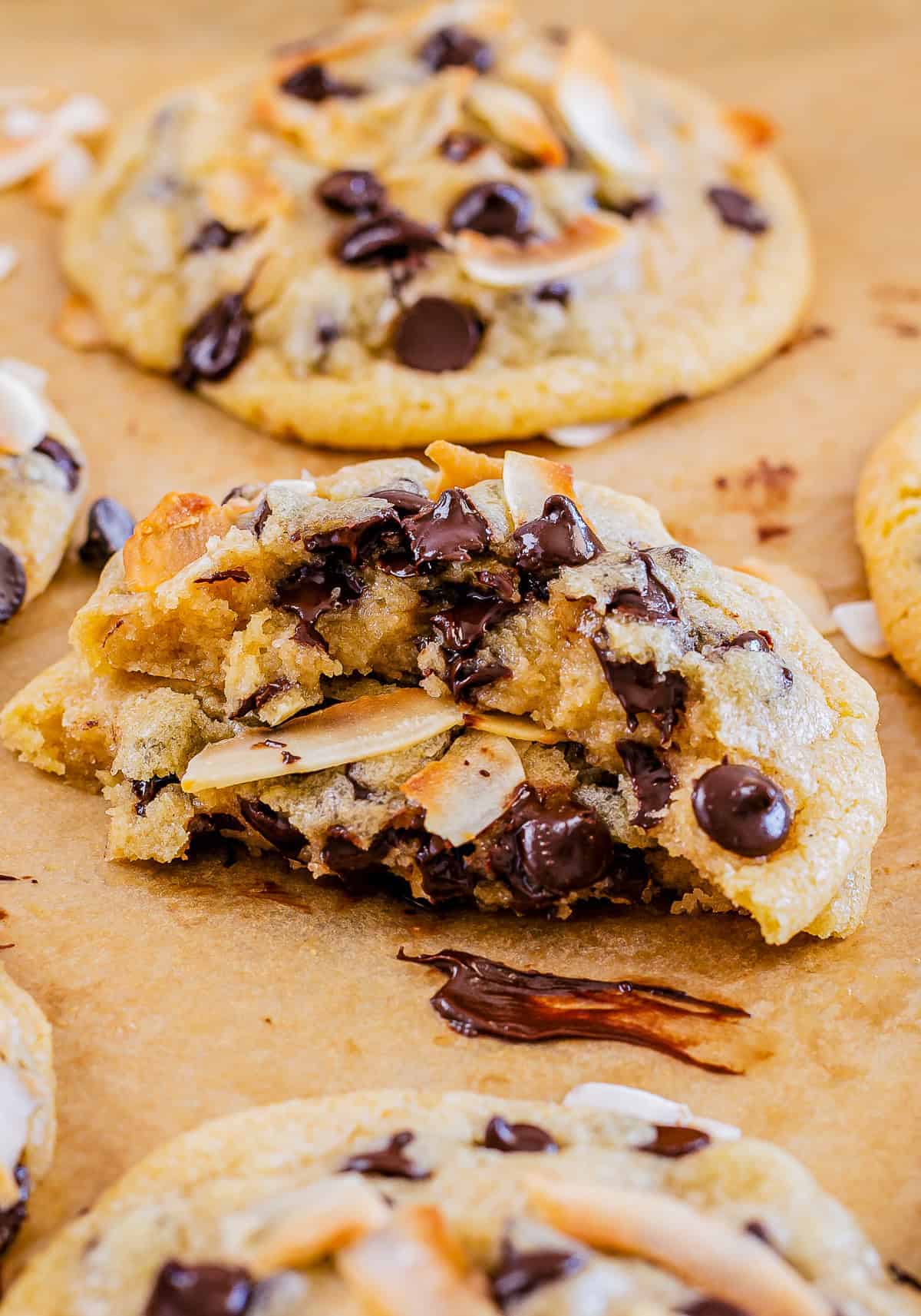 A coconut chocolate chip cookie broken in half showing gooey chocolate and coconut.