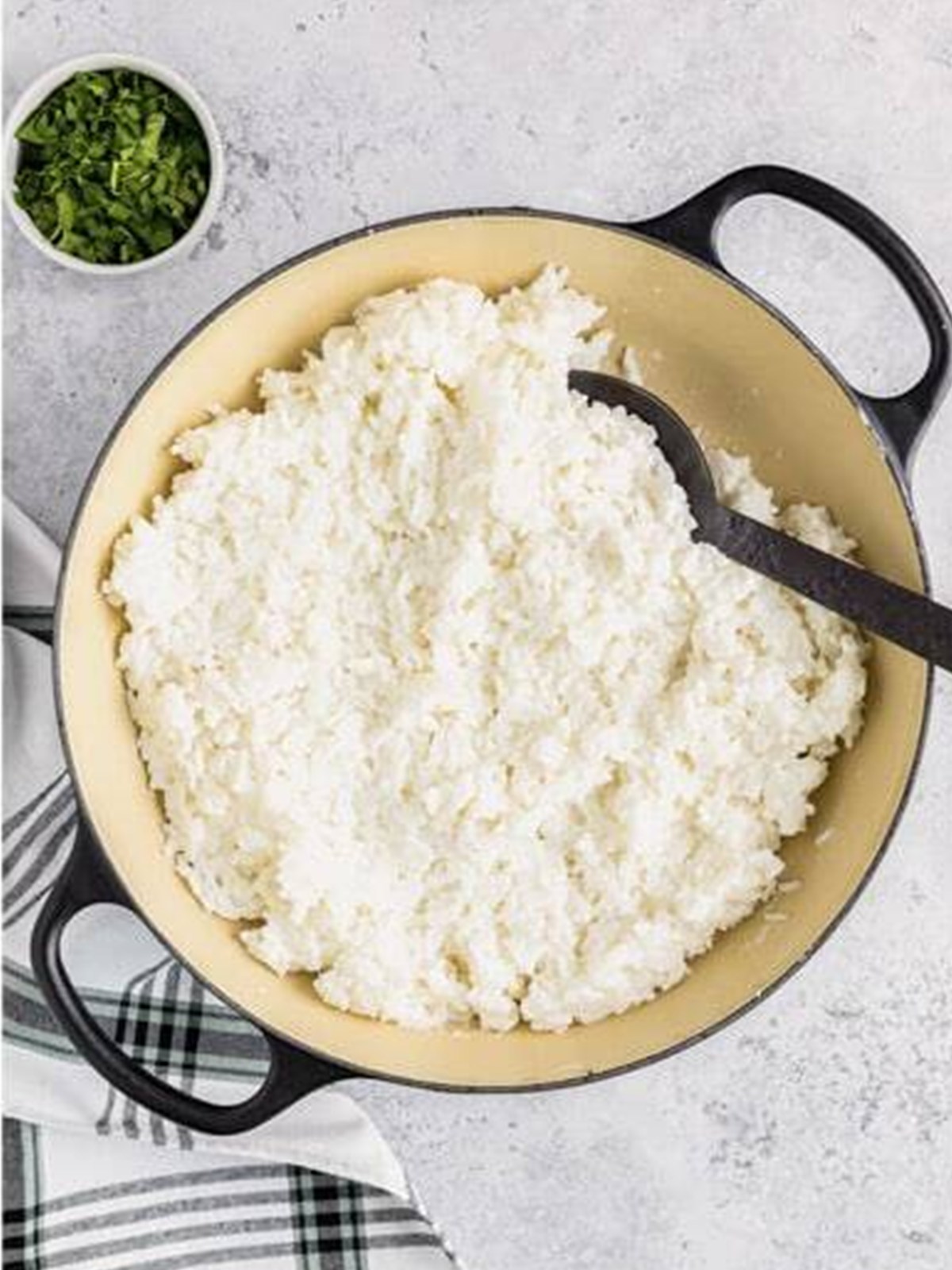 Fluffy cooked coconut rice in a pot being fluffed with a fork.