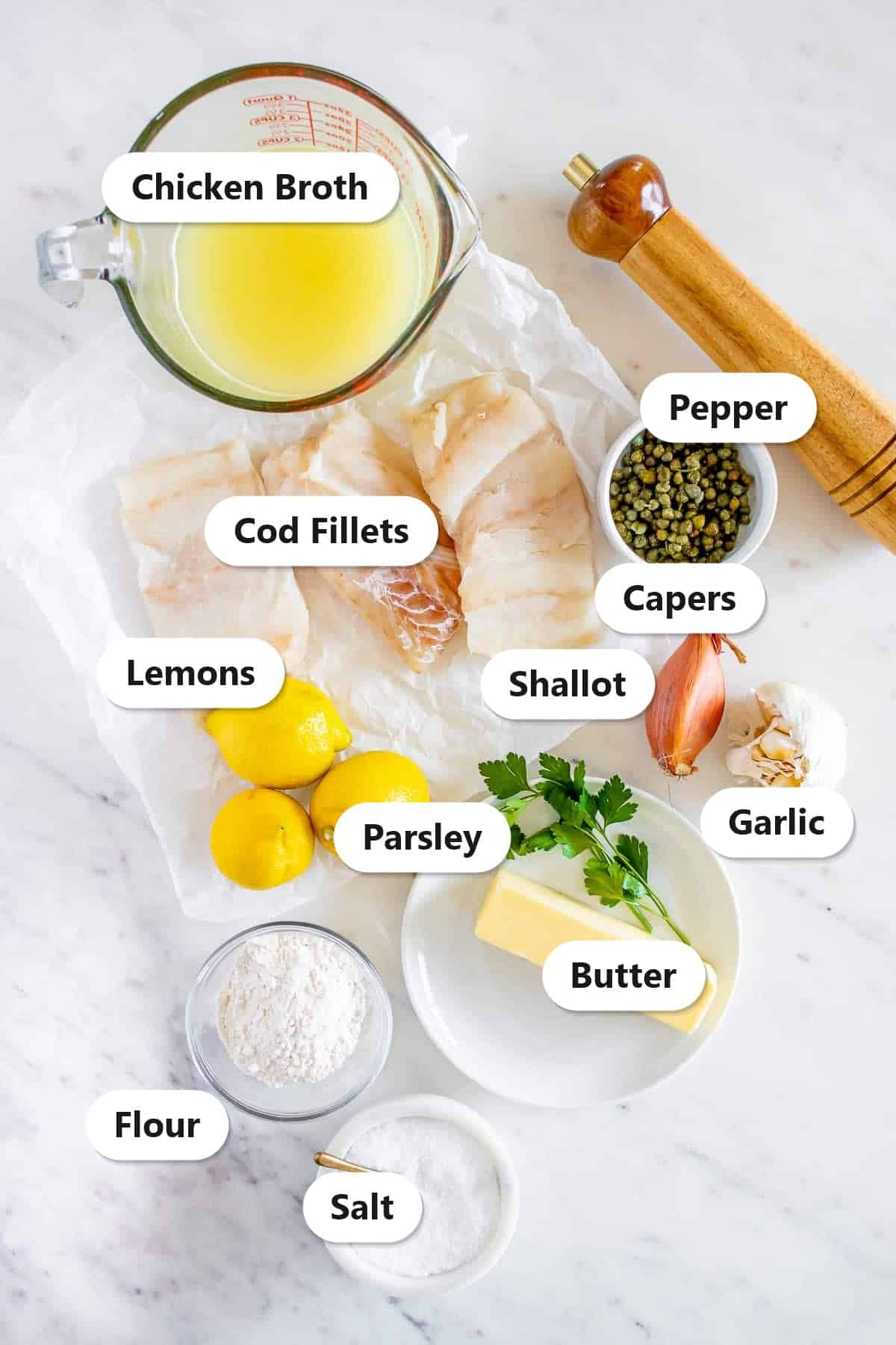 Labeled ingredients to make cod piccata including cod fillets, chicken broth, capers, shallot, garlic, lemons, butter, parsley, flour, salt, and pepper.