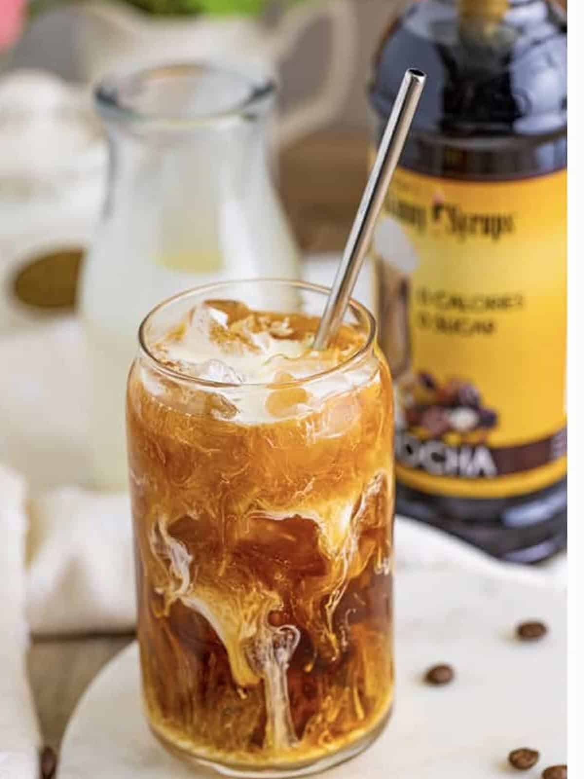 A finished iced coffee swirled with cream and coffee syrup.