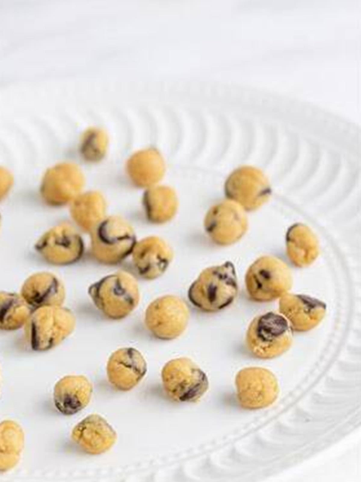 Edible cookie dough rolled into small bite size balls on a plate.
