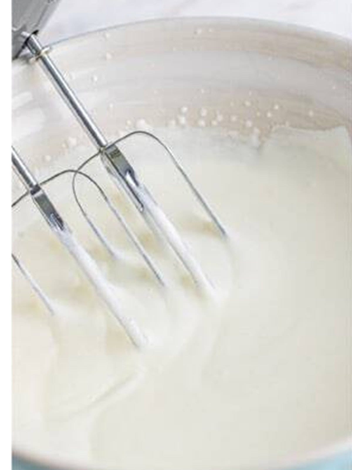 Heavy whipping cream whipped to soft peaks in a mixing bowl.