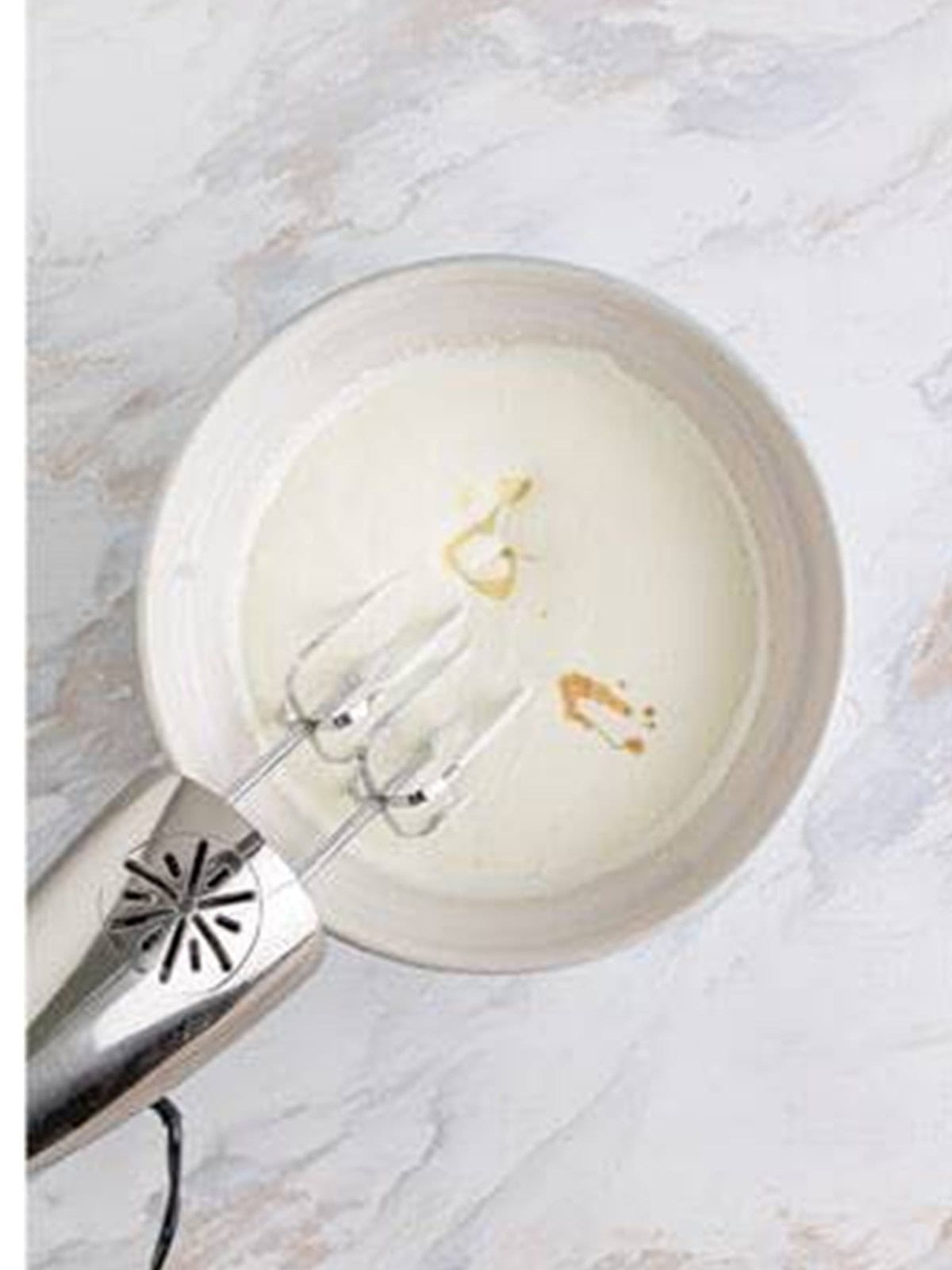Sweetened condensed milk and vanilla being whipped into the cream.