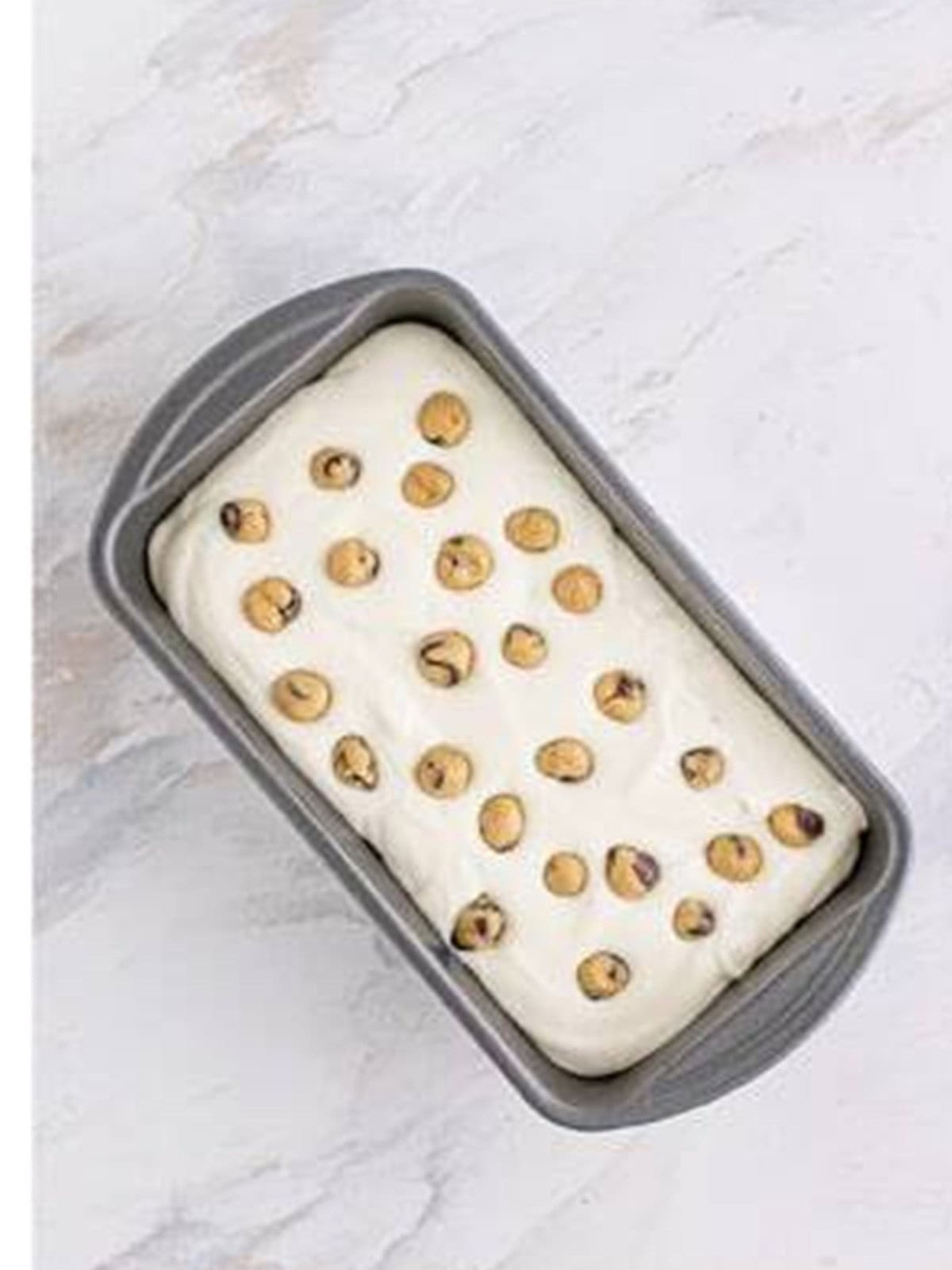 The loaf pan topped with cookie dough balls before freezing.