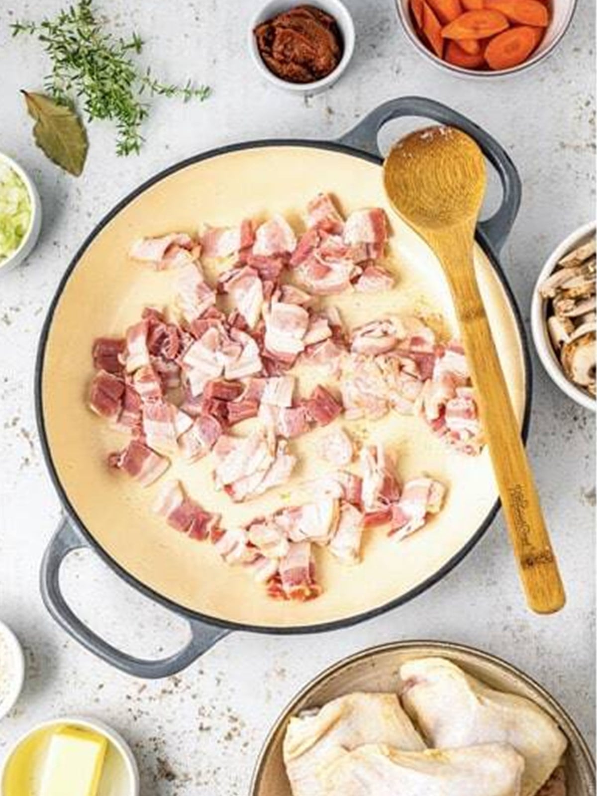 Bacon cooking until crispy in a large pan for coq au vin.