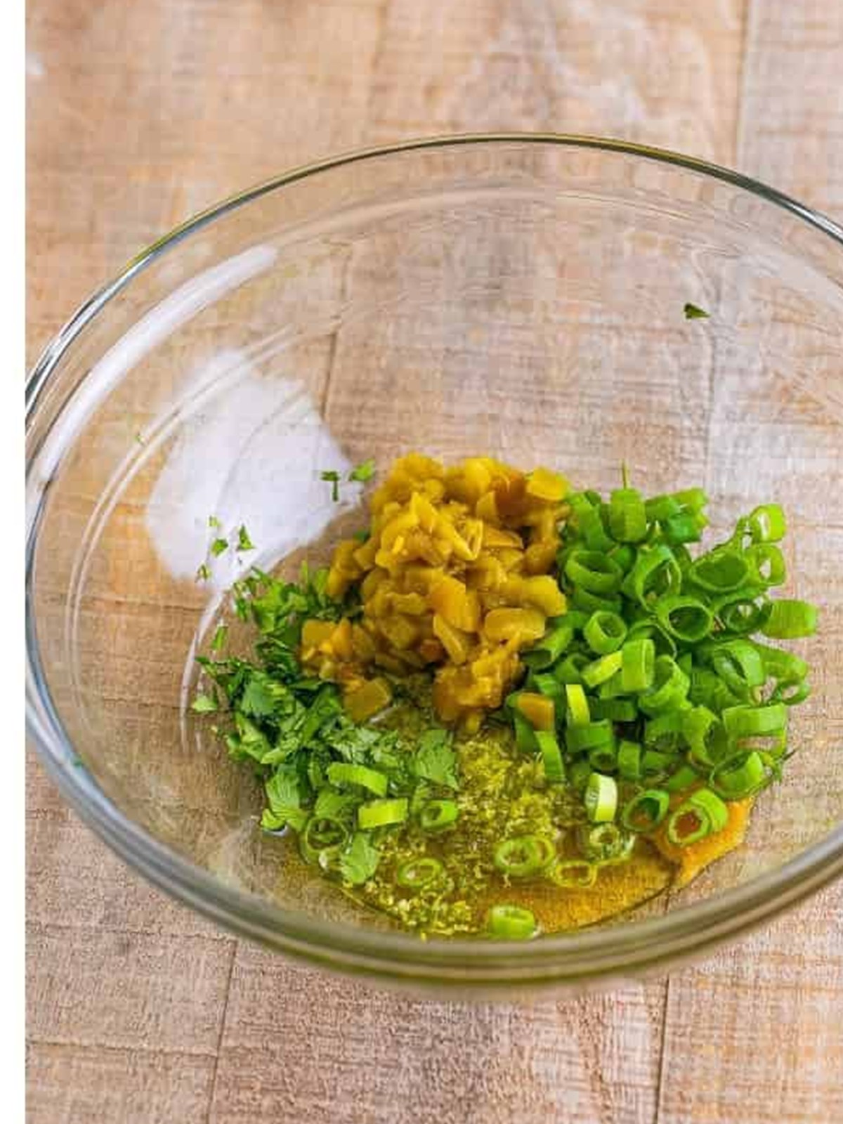 Green chiles, scallions, cilantro, honey, and lime stirred together in a bowl.