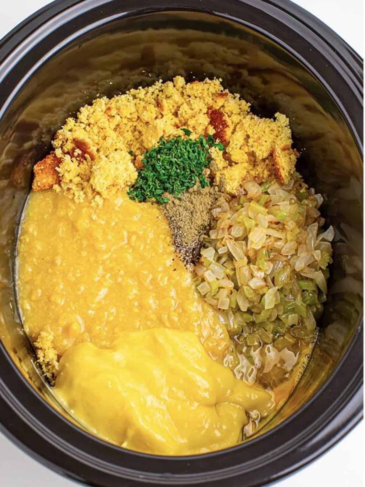 Crumbled cornbread, creamed corn, cream of chicken soup, broth, onion, celery, eggs, and seasonings added to a slow cooker.