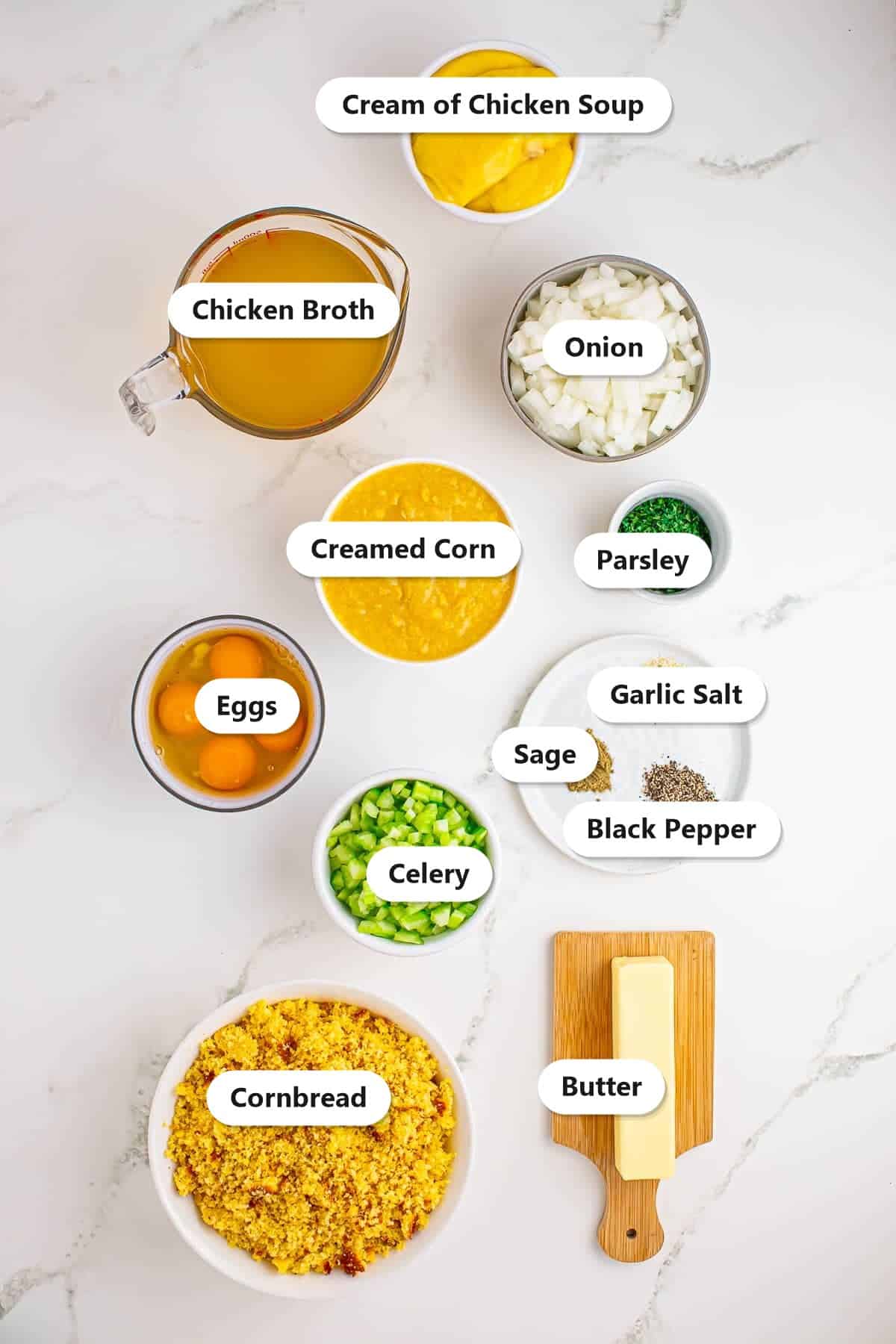 Labeled ingredients for slow cooker cornbread dressing including crumbled cornbread, creamed corn, cream of chicken soup, broth, onion, celery, eggs, butter, and seasonings.