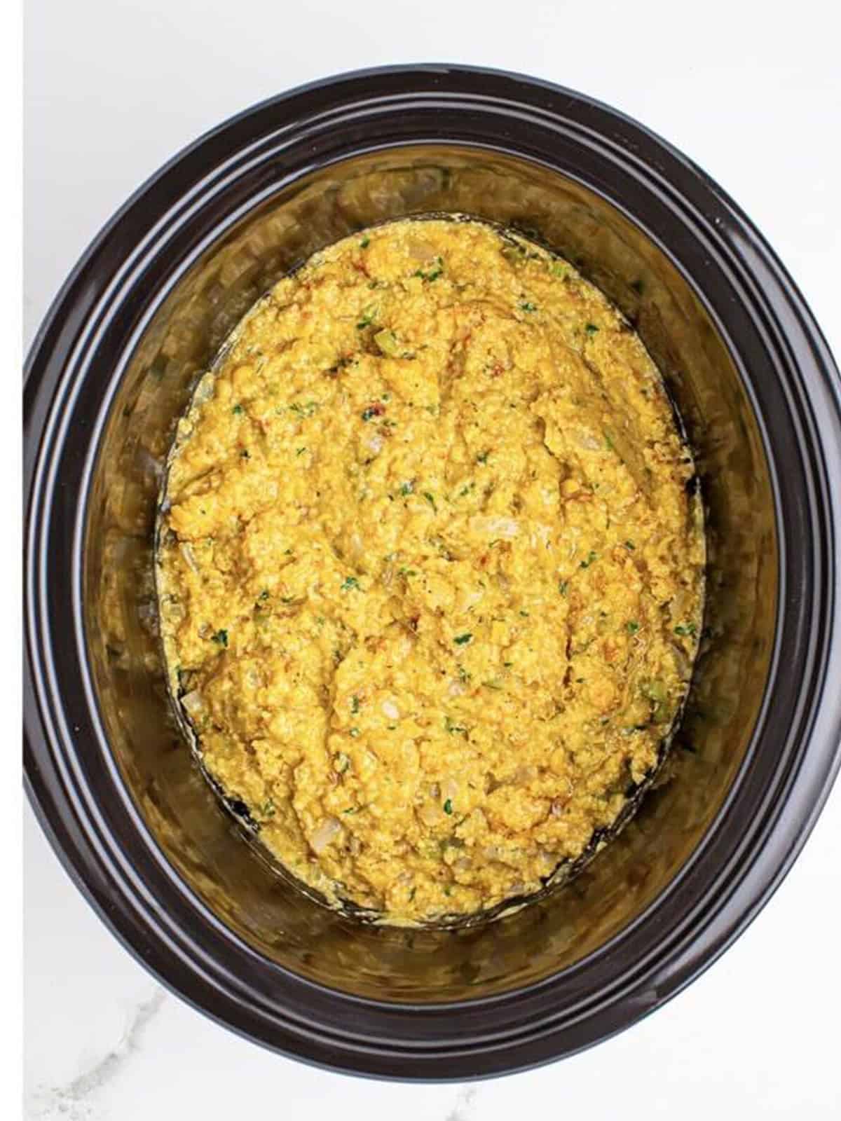 Cornbread dressing ingredients stirred together in the slow cooker.